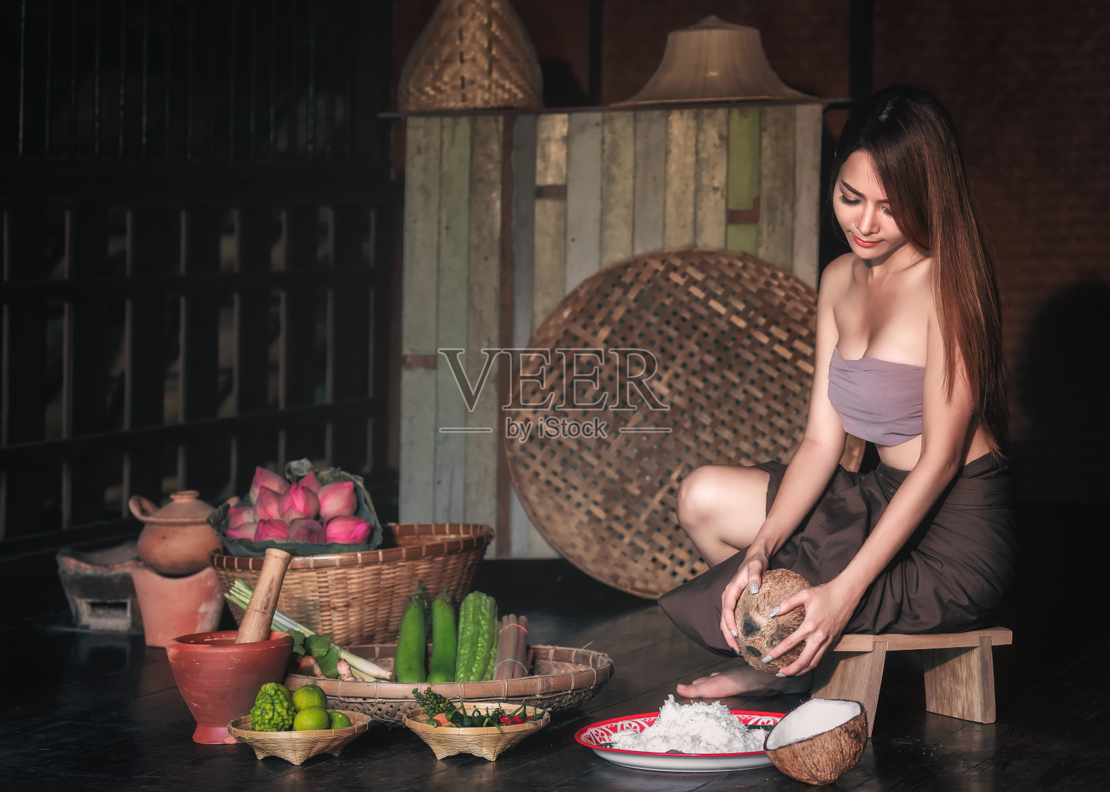 女人坐在椰子刨丝器上。照片摄影图片