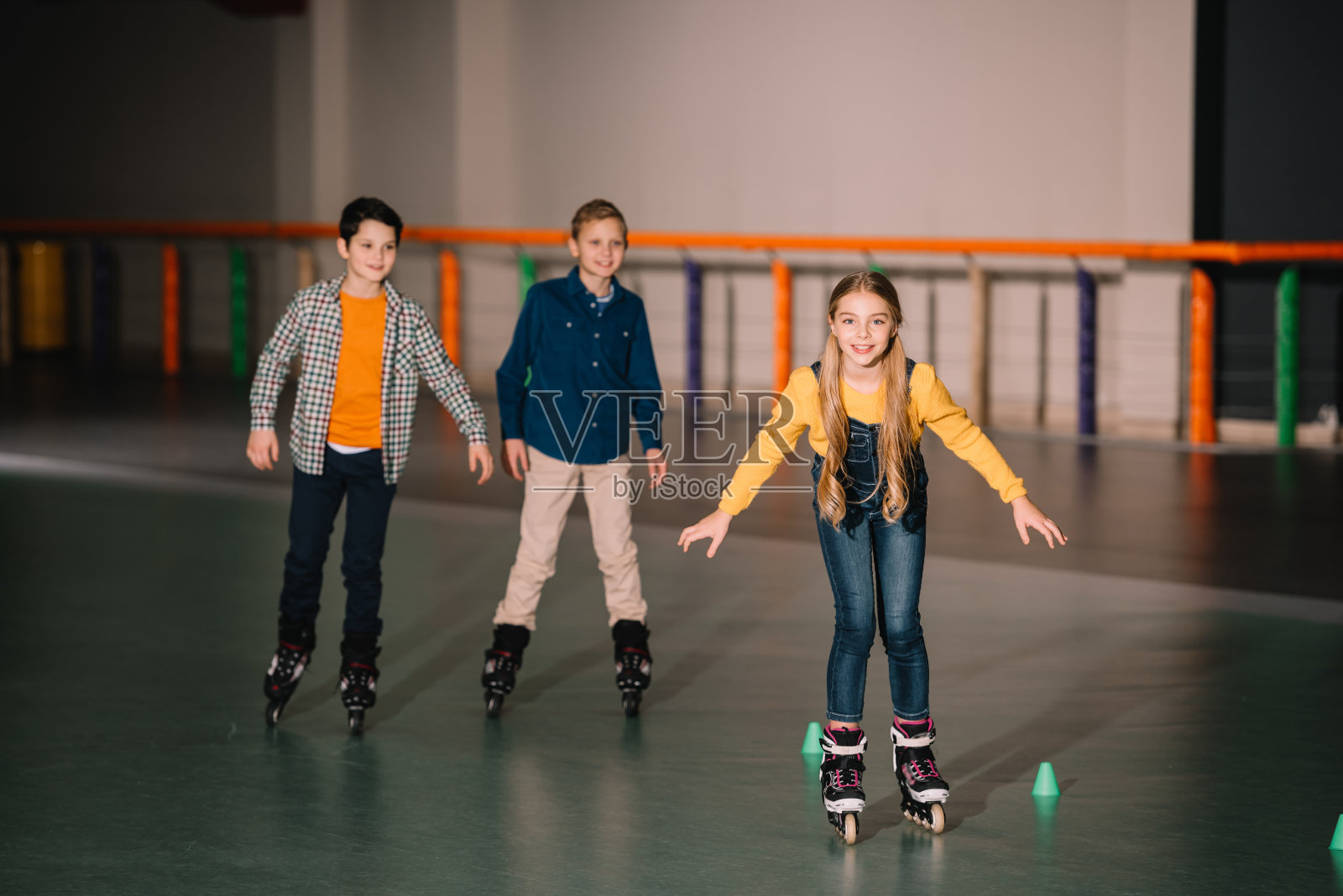 微笑的孩子们穿着旱冰鞋在溜冰场训练照片摄影图片