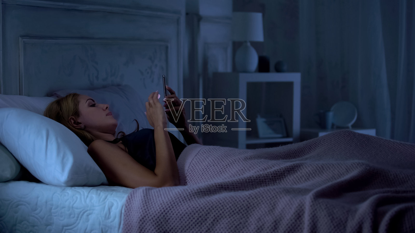 女性躺在床上用智能手机浏览社交网络，聊天照片摄影图片