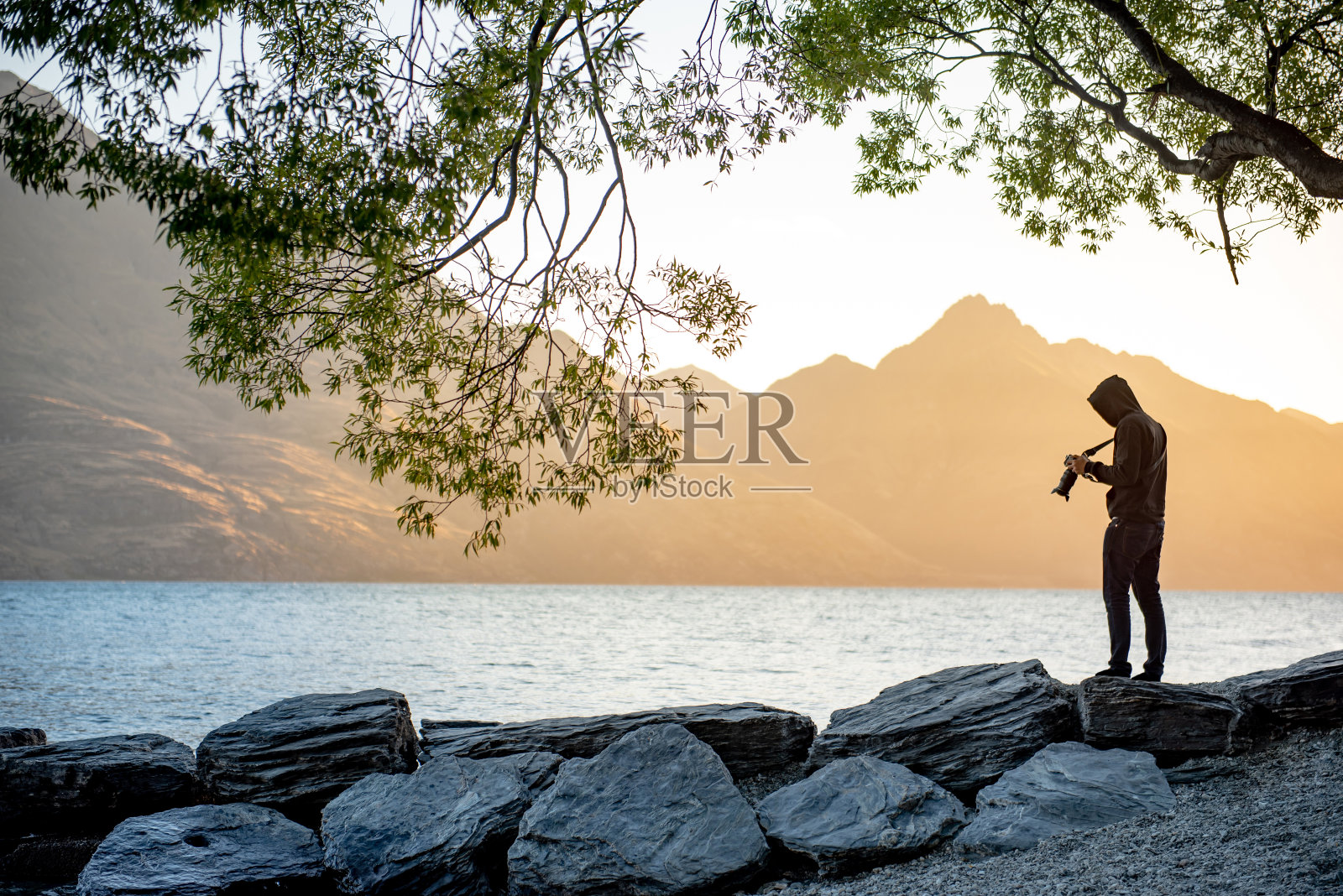 年轻的旅行者和摄影师拍摄瓦卡蒂普湖在黄金时间日落在皇后镇，南岛，新西兰，旅游和风景摄影概念照片摄影图片
