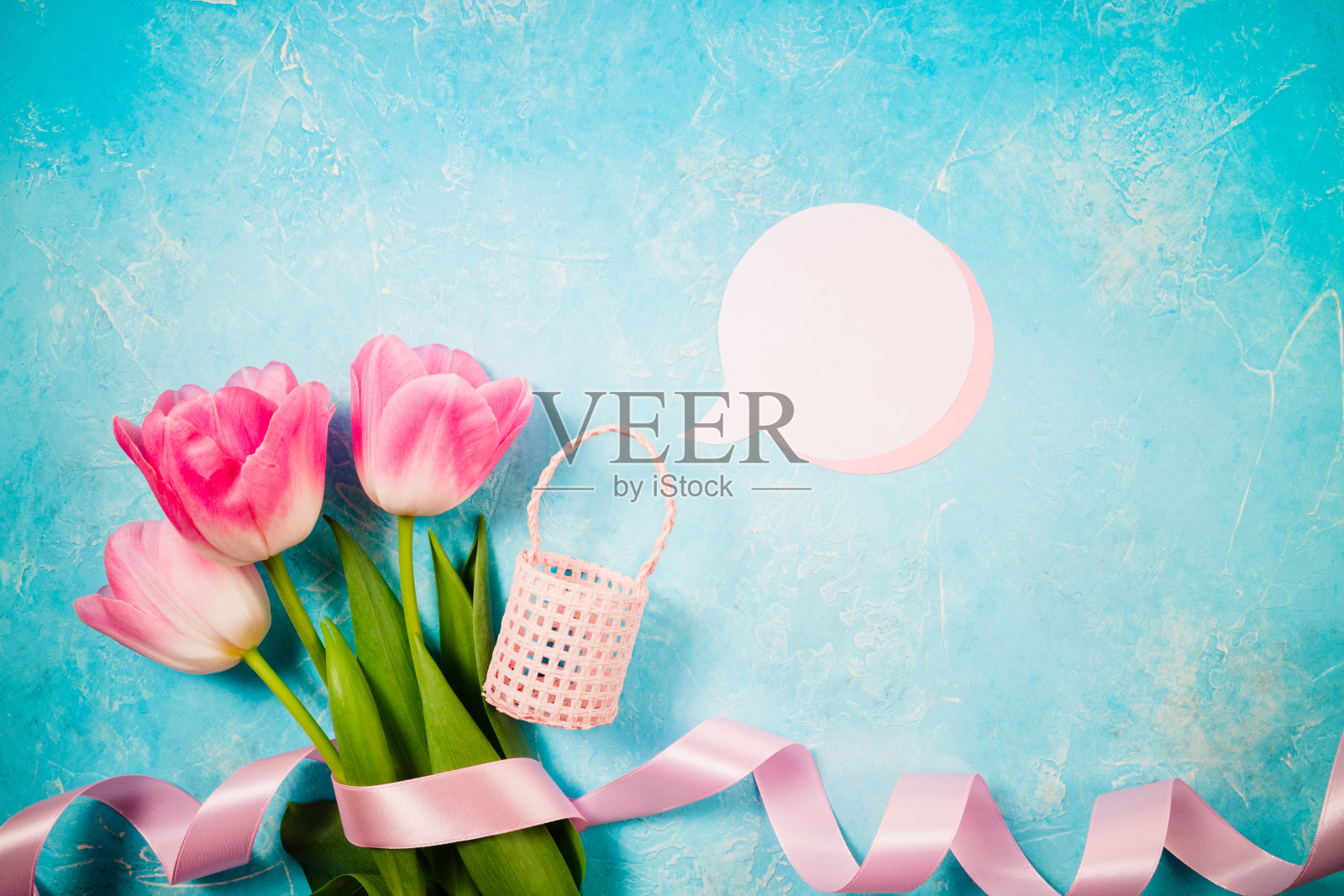 春天节日的背景。情人节、母亲节或妇女节的鲜花。粉红色的郁金香花在蓝色的背景上。俯视图照片摄影图片