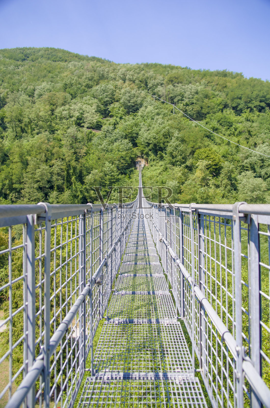 悬索桥横跨山谷和树木繁茂的山脉照片摄影图片