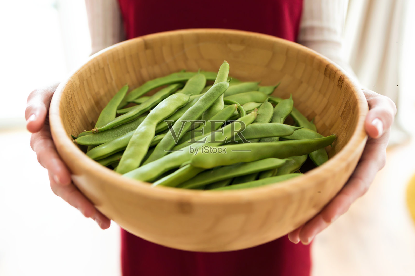 家中女子双手捧着木碗里的青豆。照片摄影图片
