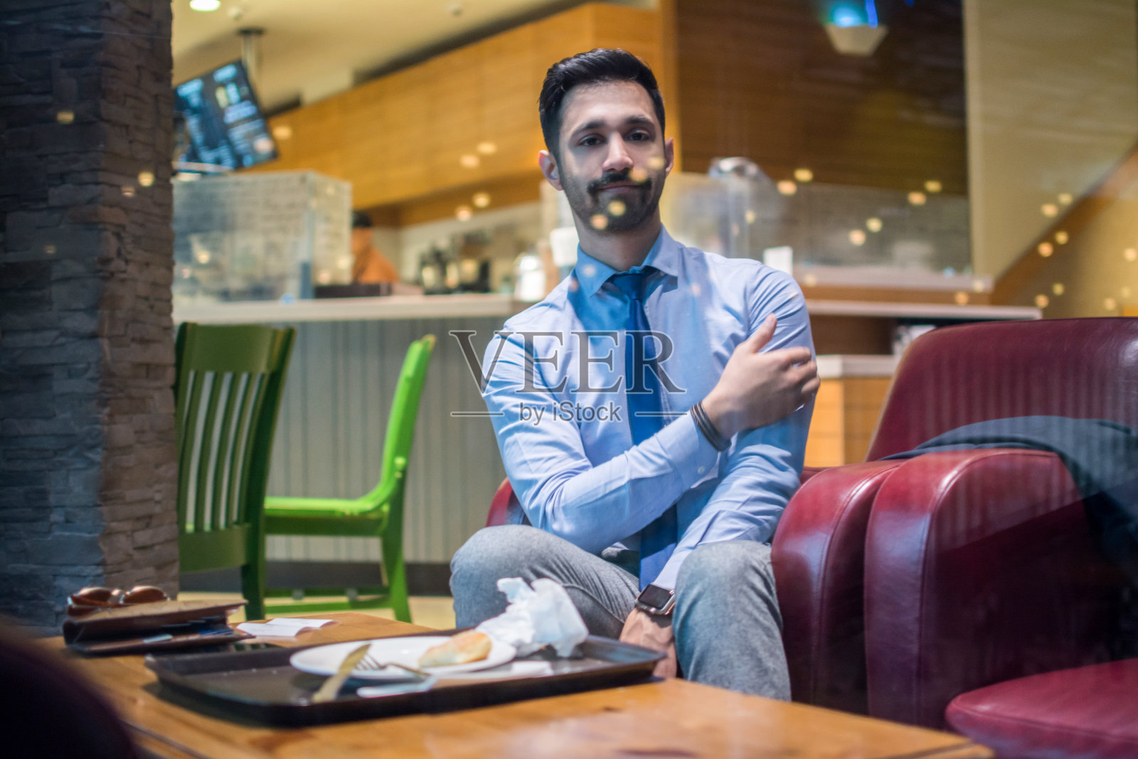 肖像英俊的年轻商人穿着商务服装坐在一个咖啡馆，看着相机照片摄影图片