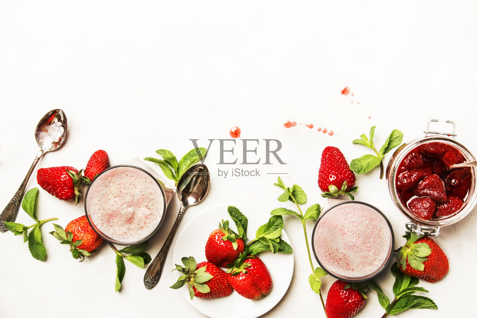 草莓牛奶冰沙与果酱，浆果和绿色薄荷，白色背景，俯视图照片摄影图片
