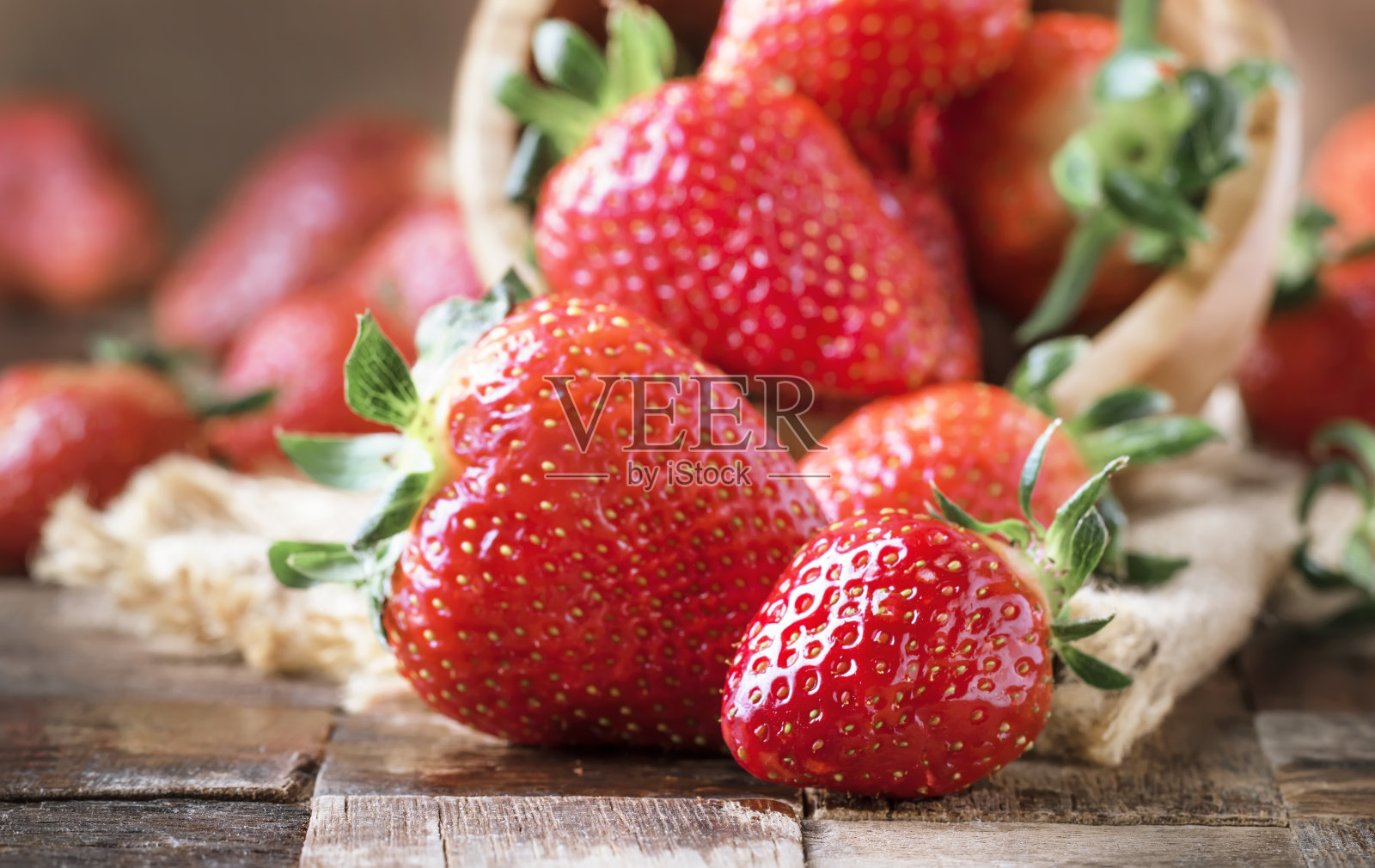 新鲜的红草莓放在复古的木制餐桌上，质朴的风格，选择性的焦点照片摄影图片