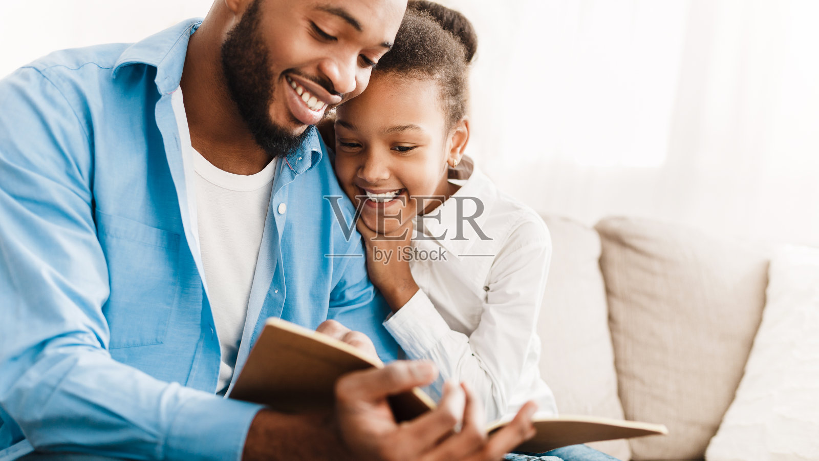 父亲和女儿一起在家里看书照片摄影图片