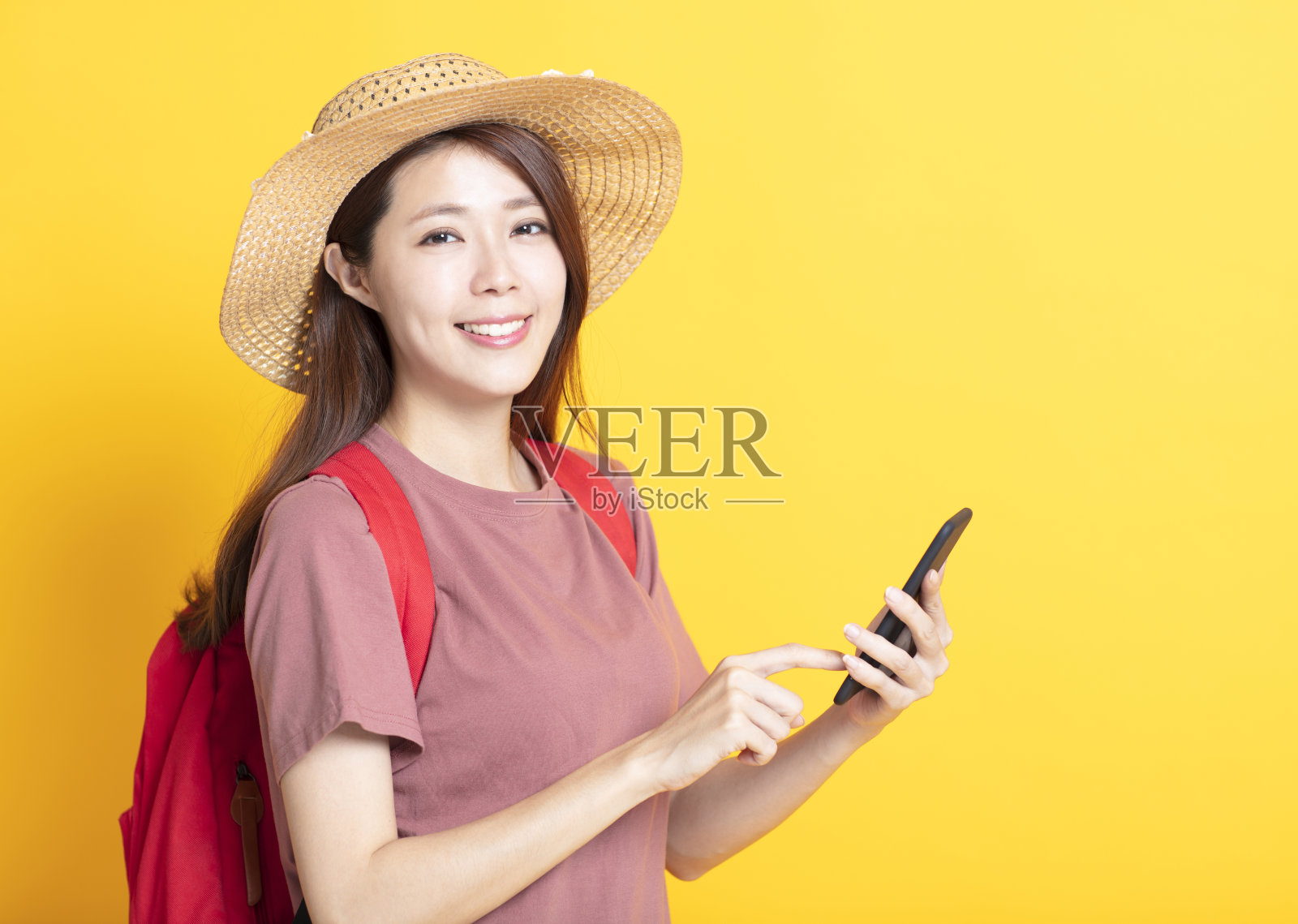 微笑的年轻女子在夏天的帽子和使用智能手机照片摄影图片