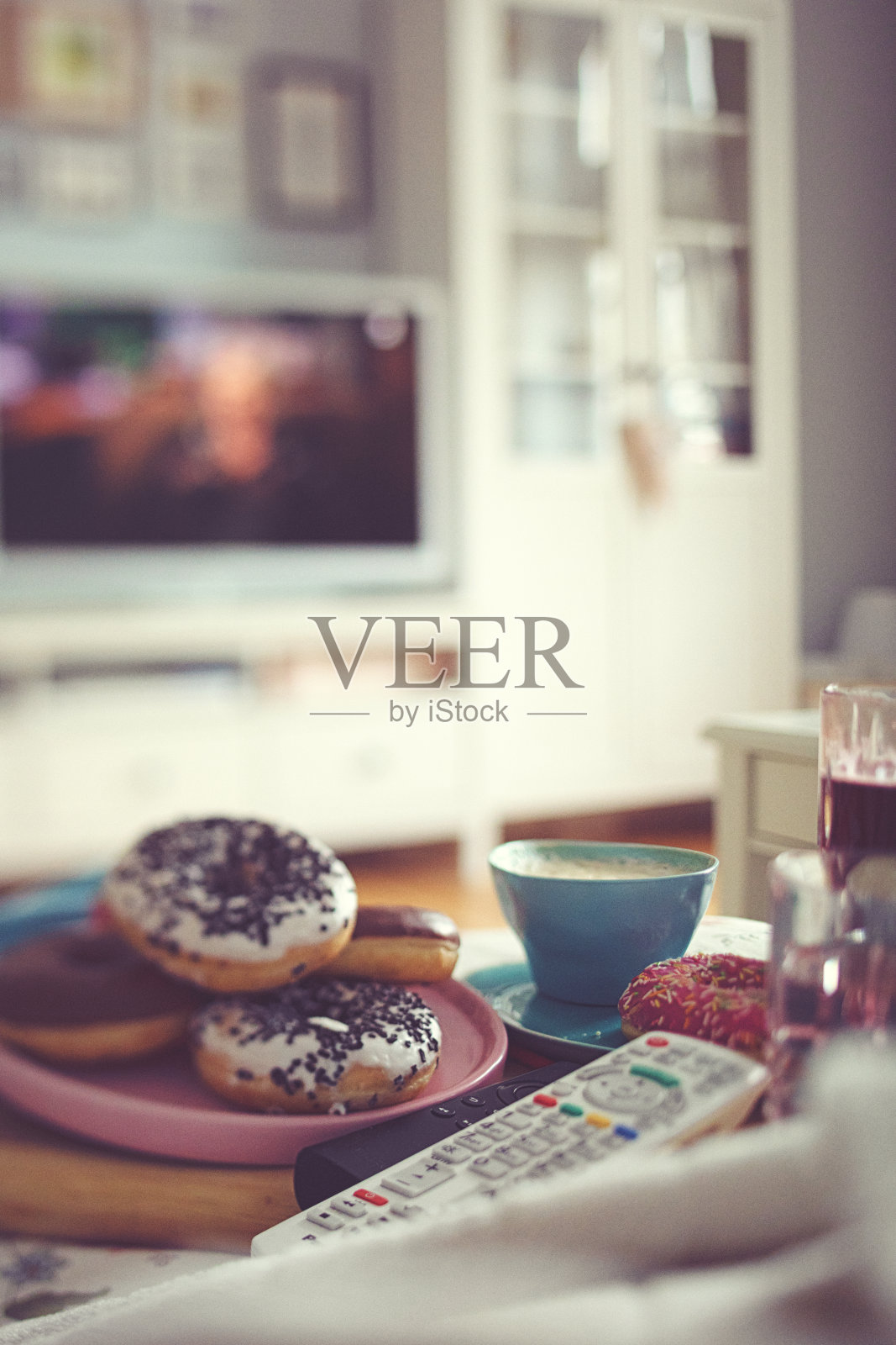 五彩缤纷的甜甜圈、咖啡、柠檬水，惬意地度过一个看电视的下午照片摄影图片