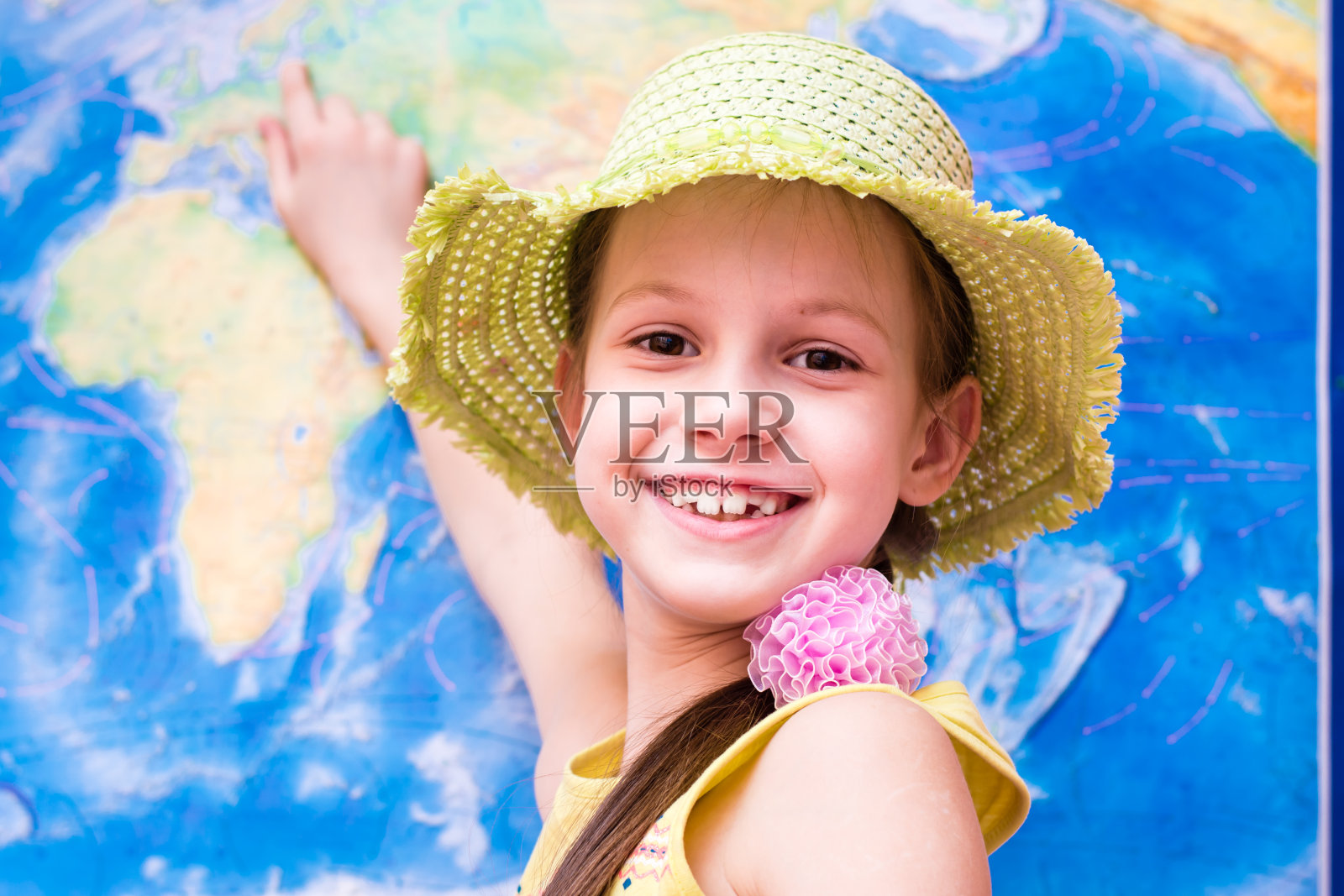 戴着帽子的女孩微笑着展示世界地图照片摄影图片