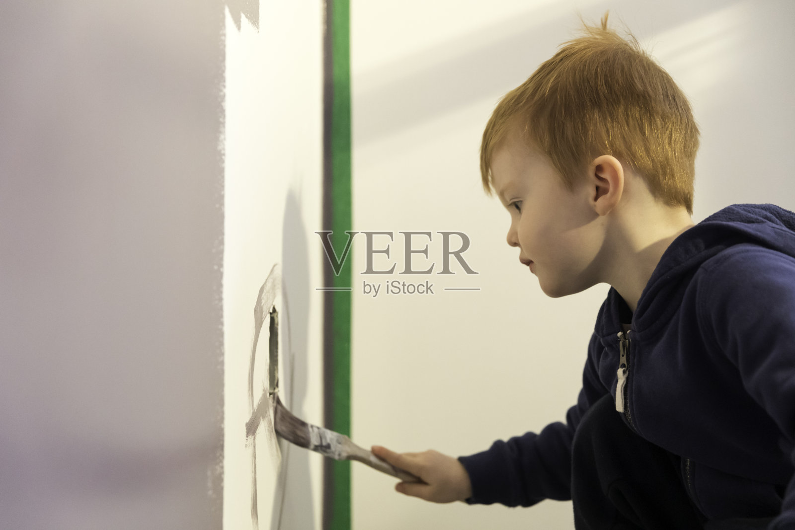 小男孩学习如何油漆他的房子的墙壁照片摄影图片