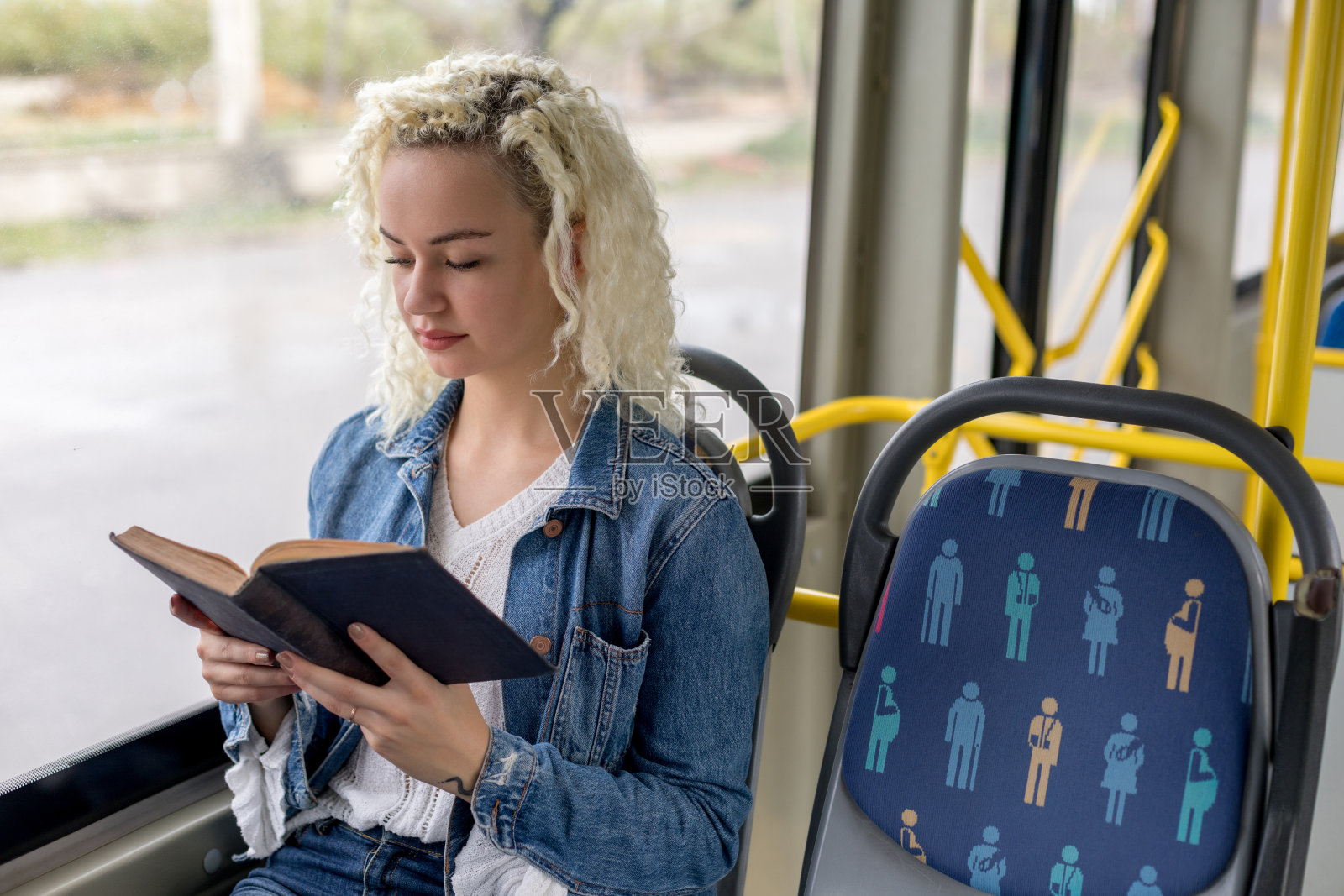 那位年轻女子正在公共汽车上看书照片摄影图片