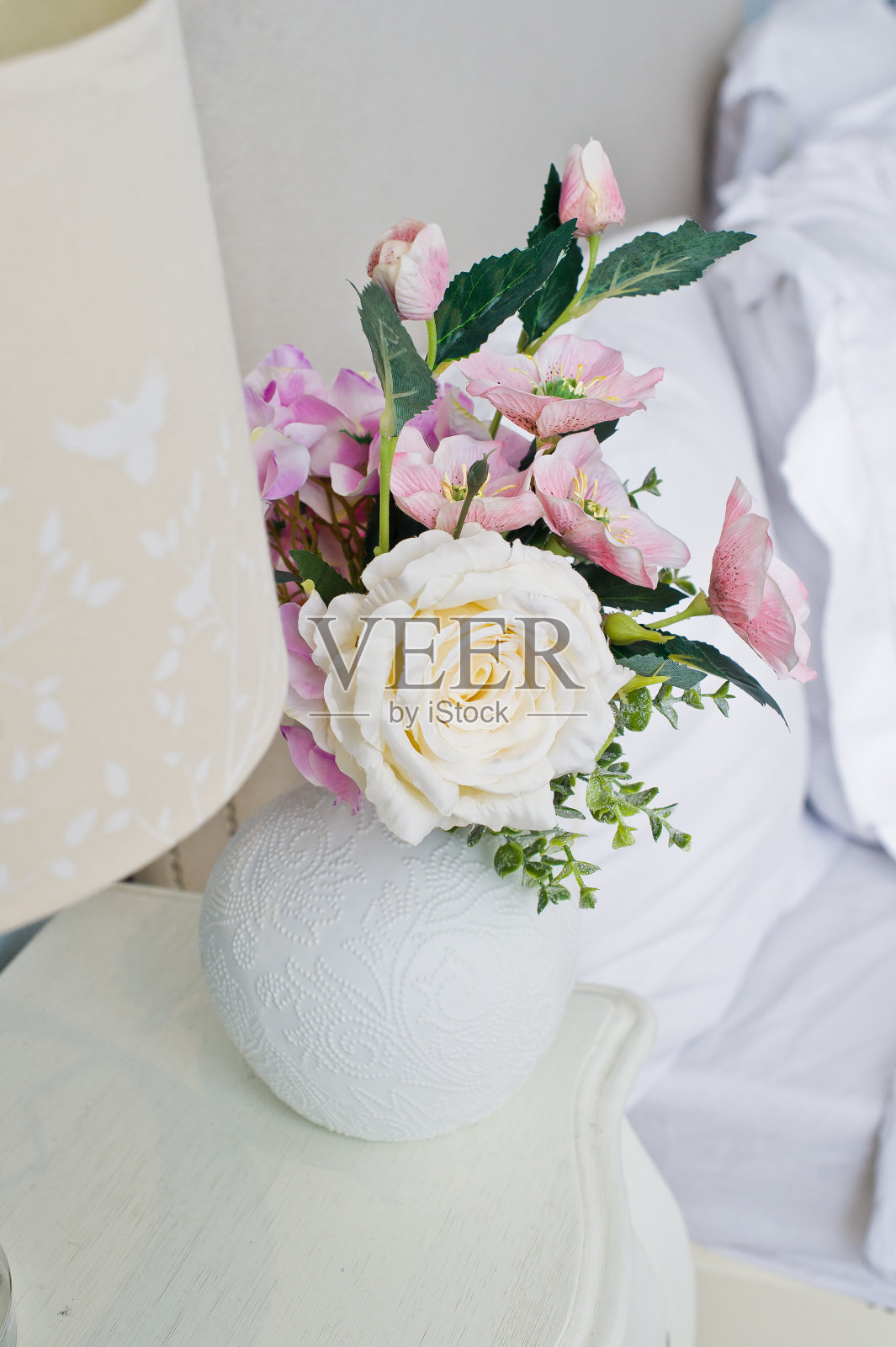 一瓶花，白玫瑰。床头柜，时装屋内部。照片摄影图片