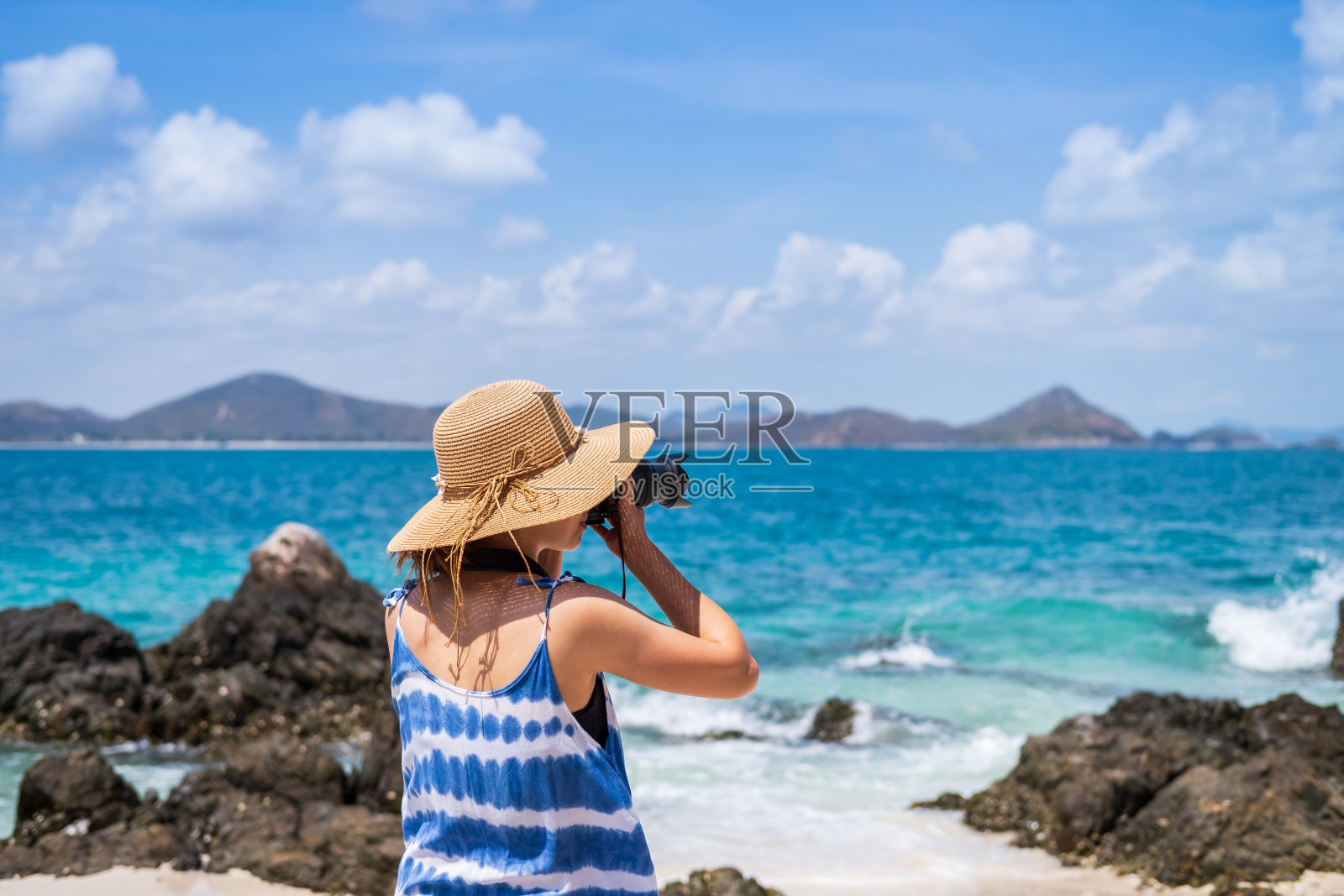 年轻女子在热带海滩拍照，暑假和旅游概念照片摄影图片