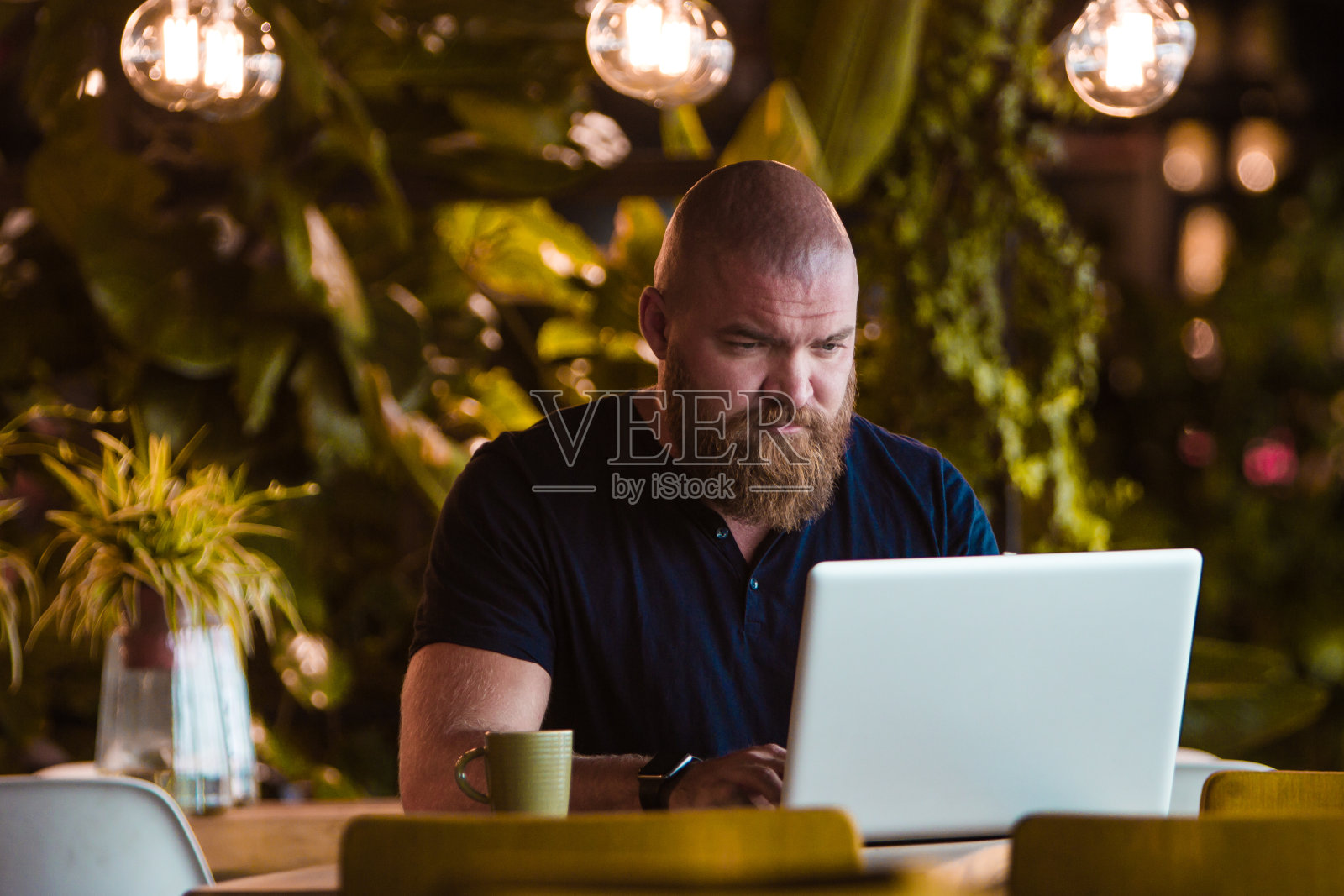 在酒吧里用笔记本电脑工作的大胡子男人照片摄影图片