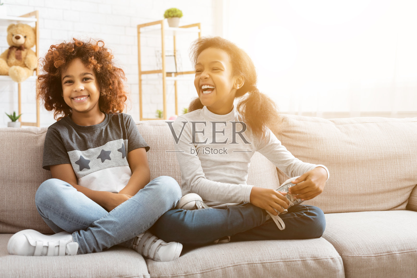 快乐的非裔美国女孩坐在家里的沙发上照片摄影图片