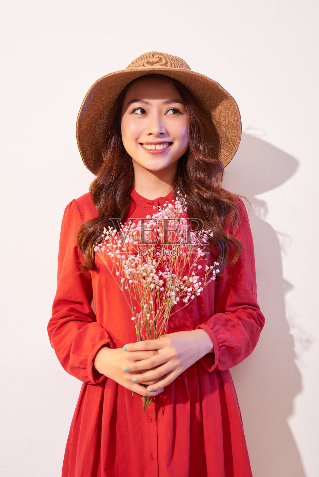 一个可爱的年轻女子在夏季连衣裙和草帽摆姿势，同时拿着一束鲜花照片摄影图片
