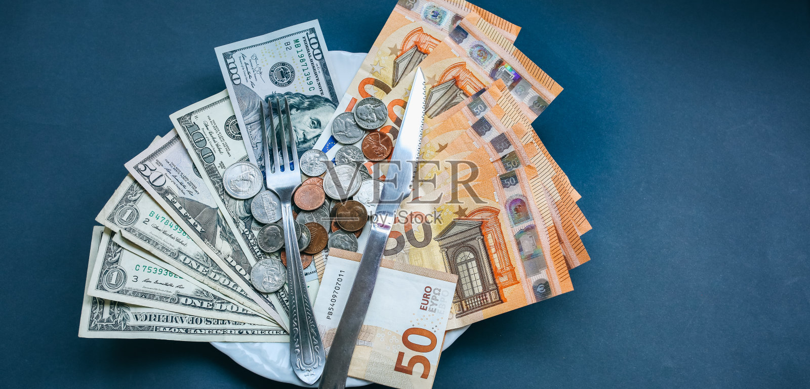 钱用刀叉躺在盘子里。欧元和美元照片。贪婪腐败的概念。贿赂的想法。美分硬币。通货膨胀率。价格的增长。贫穷与富有。照片摄影图片
