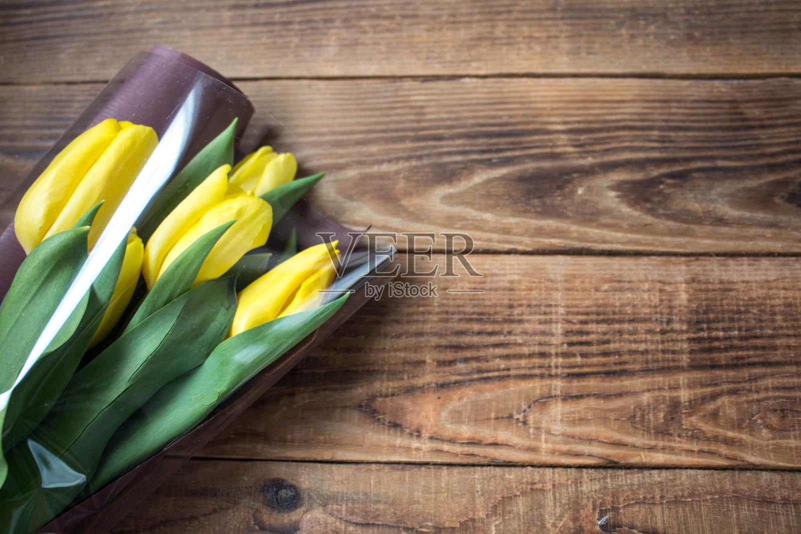 一个漂亮的黄色郁金香在包装上的木制背景照片摄影图片