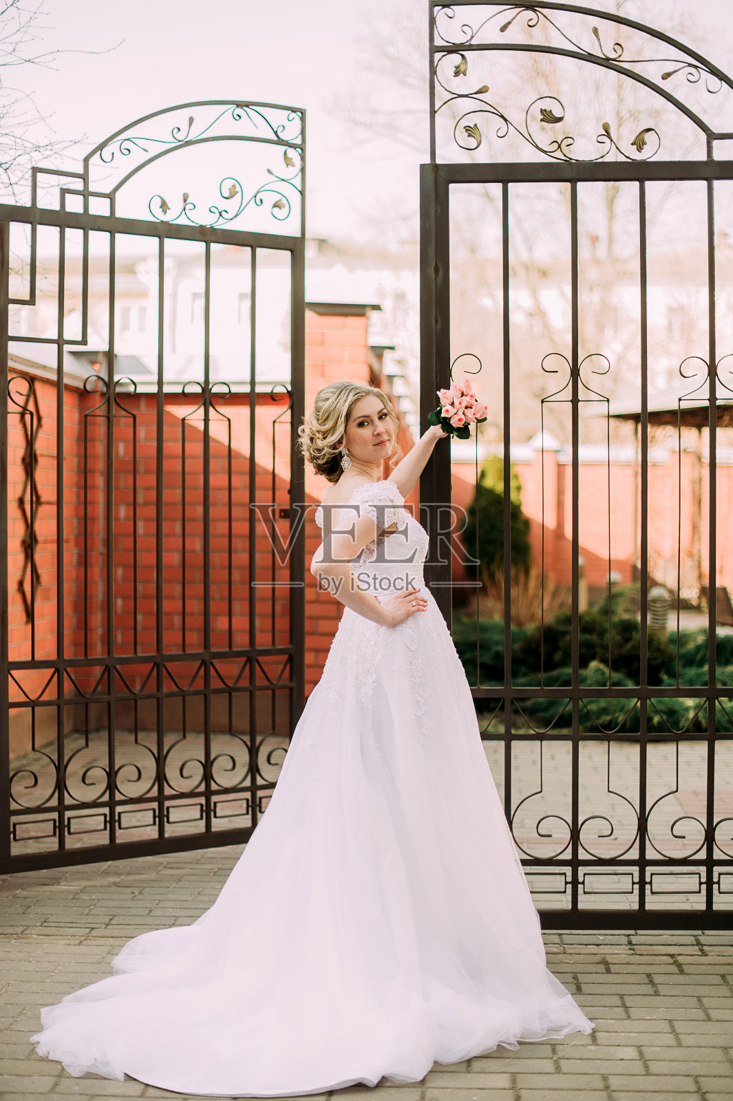 美丽的新娘肖像与新娘花束摆姿势在她的婚礼当天照片摄影图片