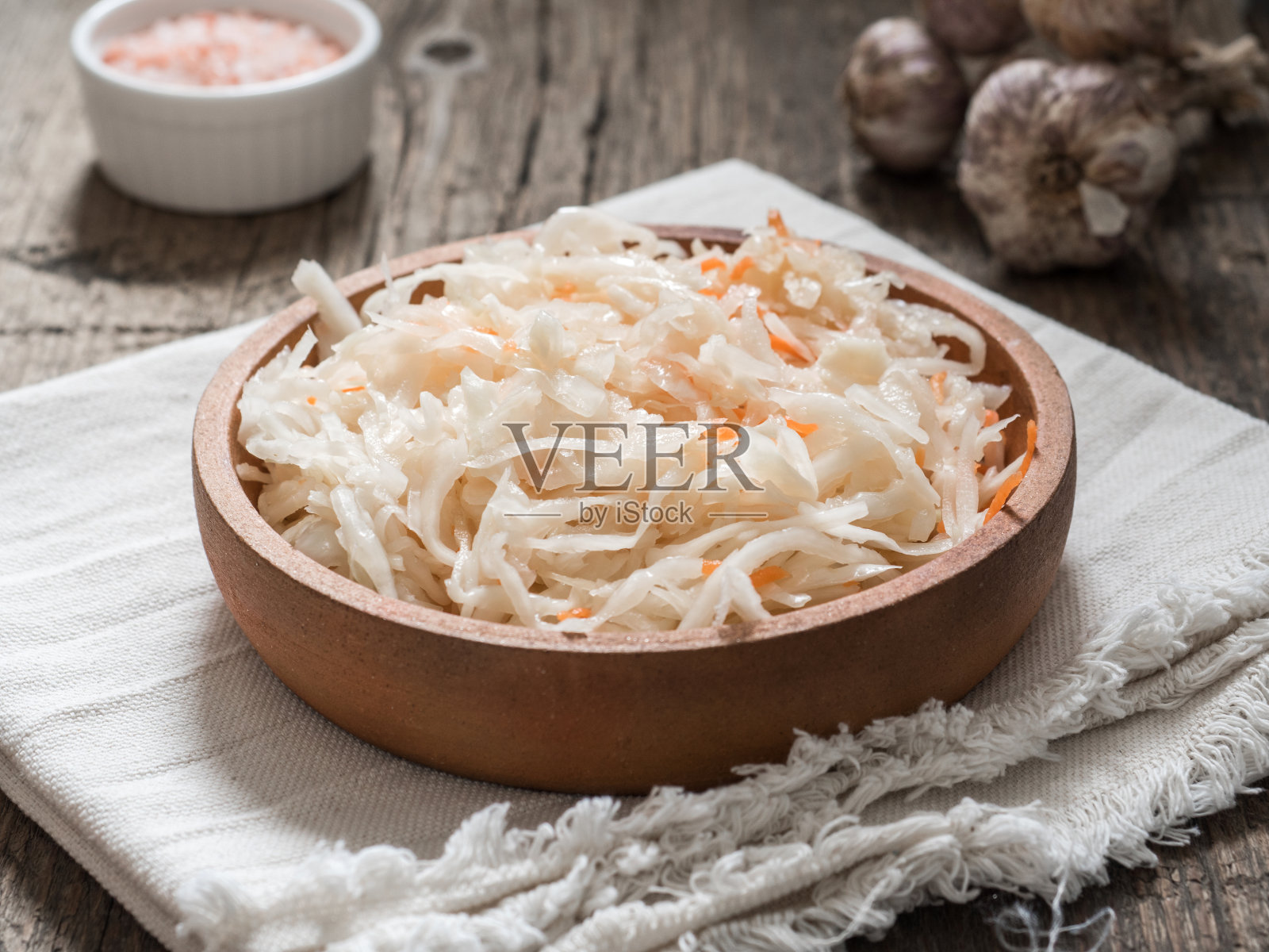 泡菜。在木桌上的棕色粘土盘子里发酵的卷心菜。健康的素食和最好的天然益生菌照片摄影图片