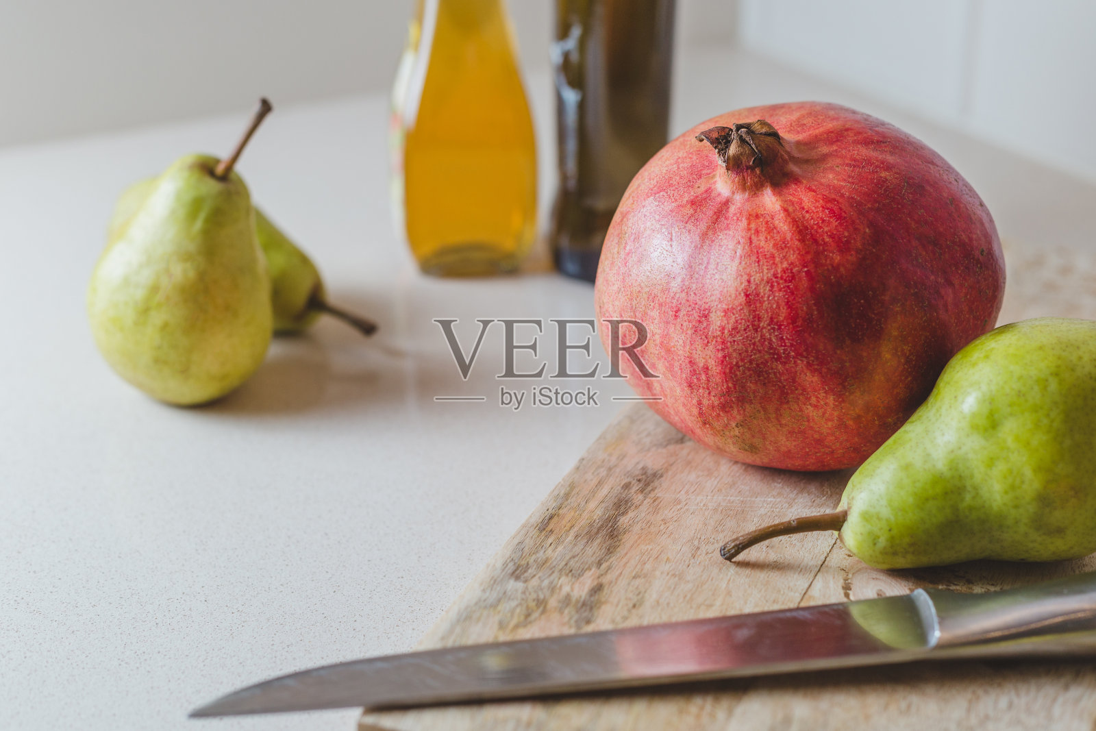 新鲜的梨和石榴在厨房的切木板上照片摄影图片