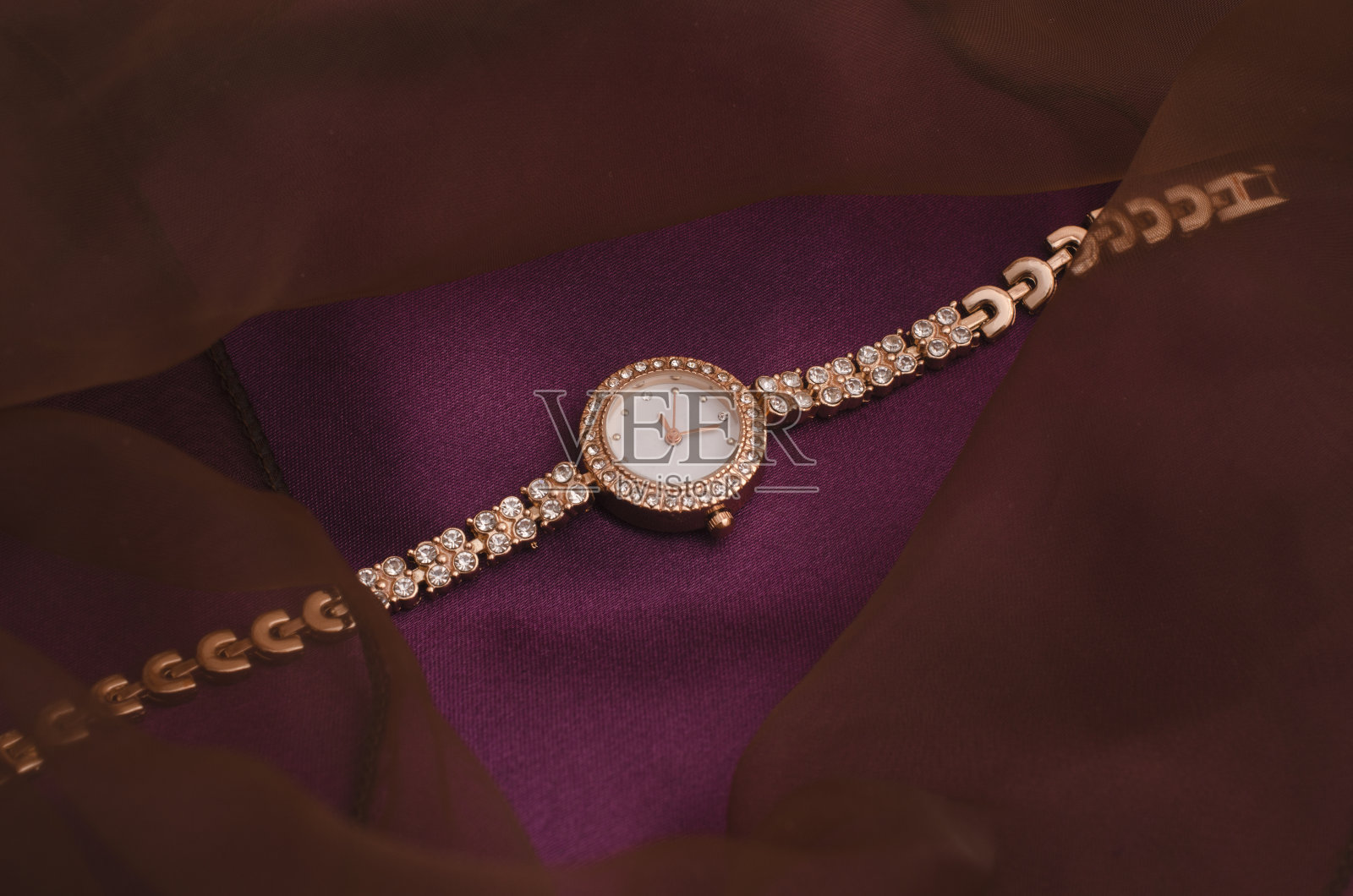 女性的黄金腕表与钻石隔离在丝绸上照片摄影图片