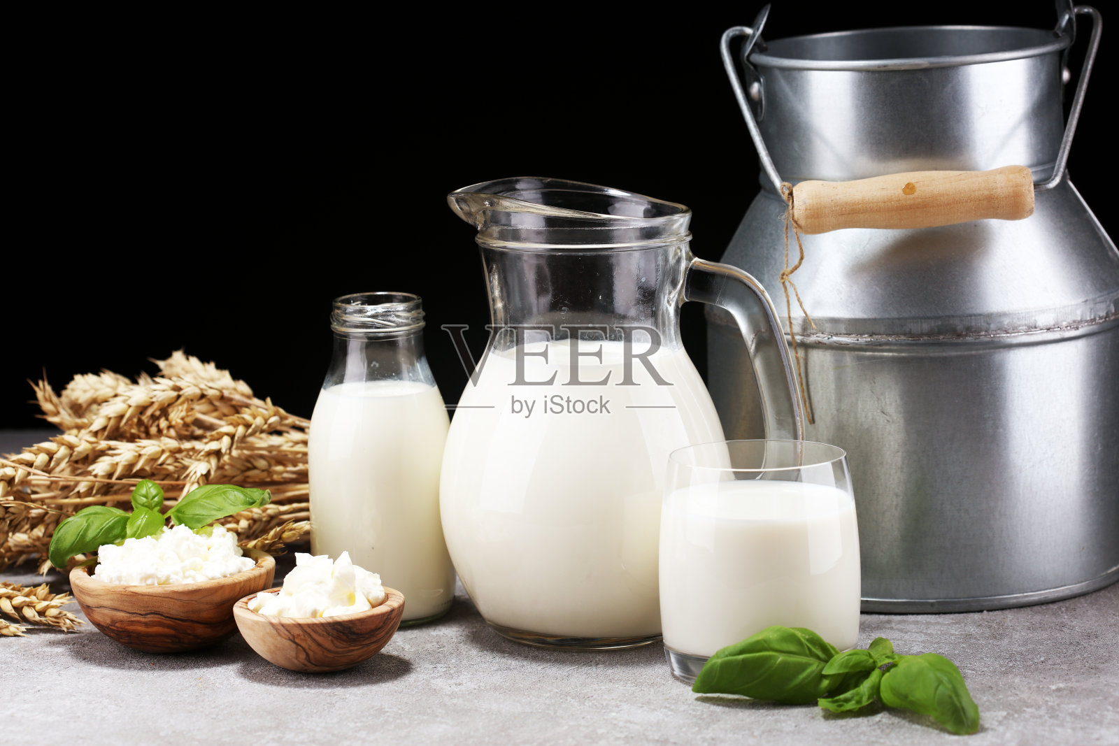 牛奶产品。美味健康的乳制品摆在桌上。酸奶油放在白碗里，奶酪碗里，奶油放在银行和牛奶罐里，玻璃瓶和玻璃杯里照片摄影图片