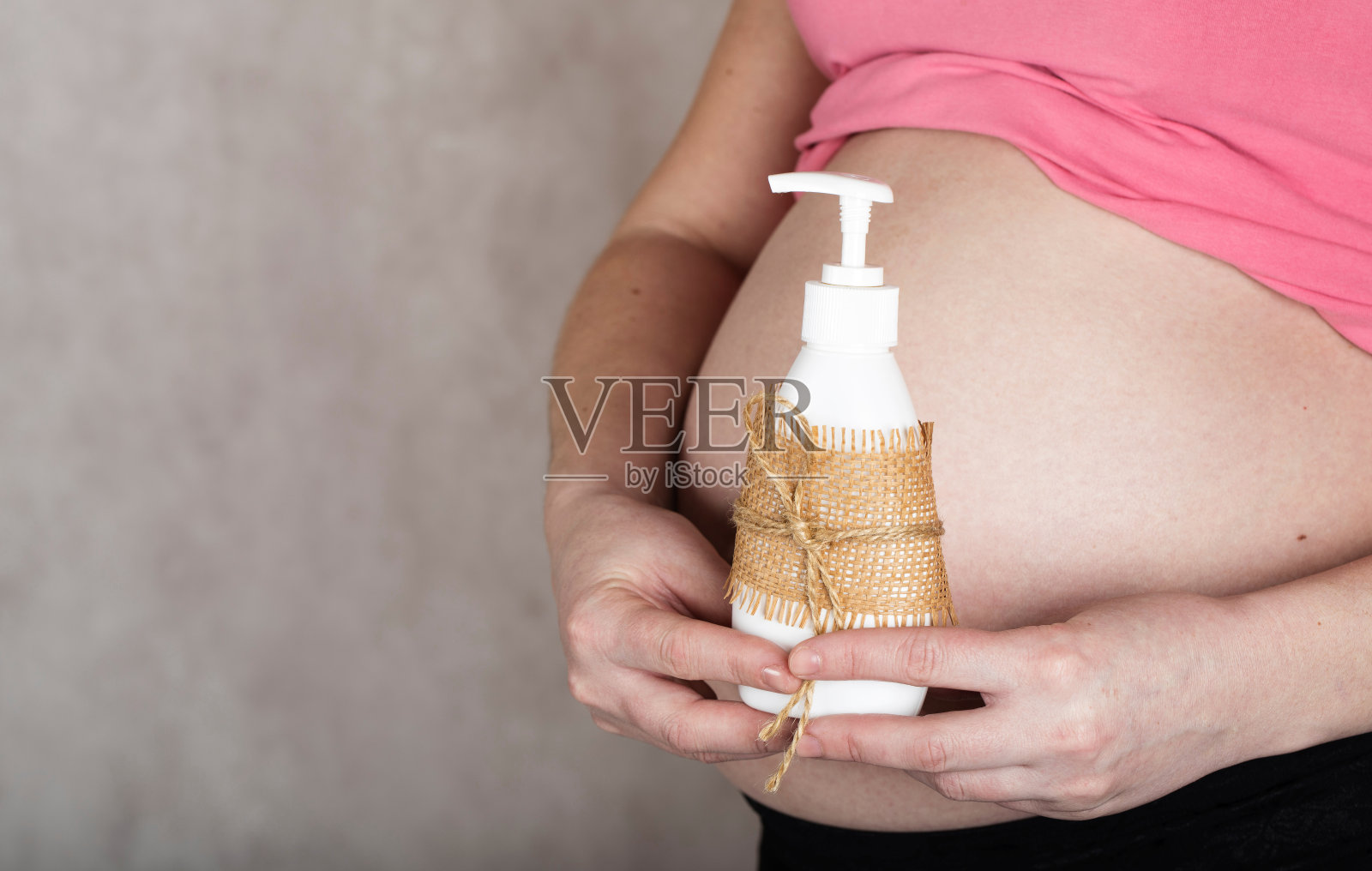 年轻的孕妇在30到35岁之间，保持一个塑料瓶亲密的凝胶。照片摄影图片