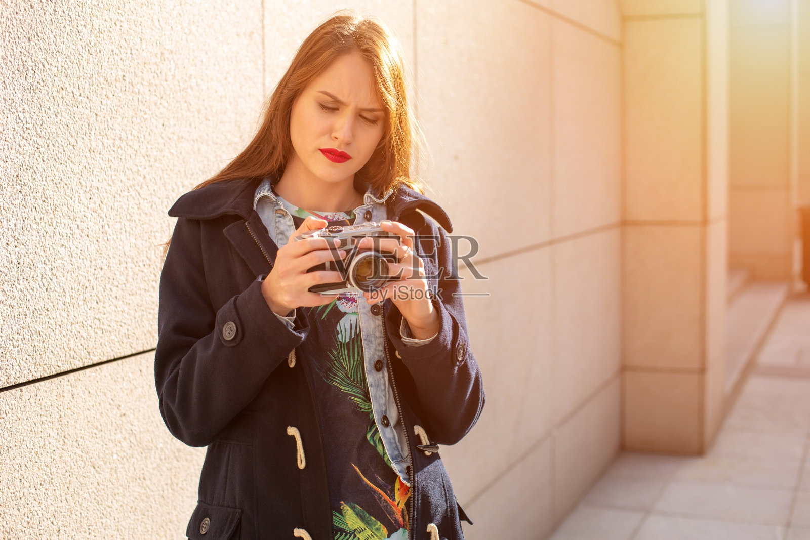 快乐的潮妹在城市街道上用复古相机拍照。太阳耀斑照片摄影图片