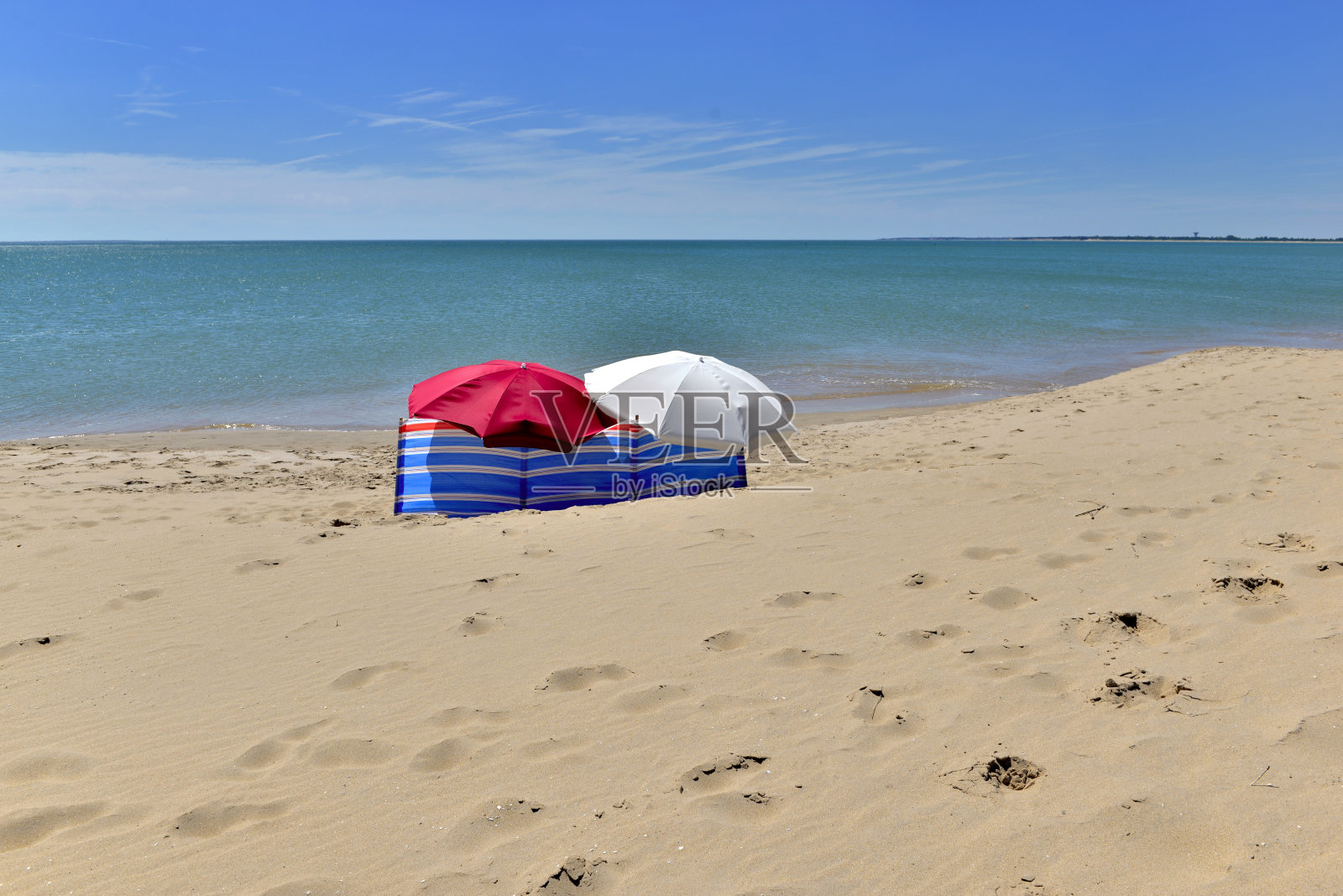 遮阳伞孤立在蓝色的大海前面的沙滩上照片摄影图片