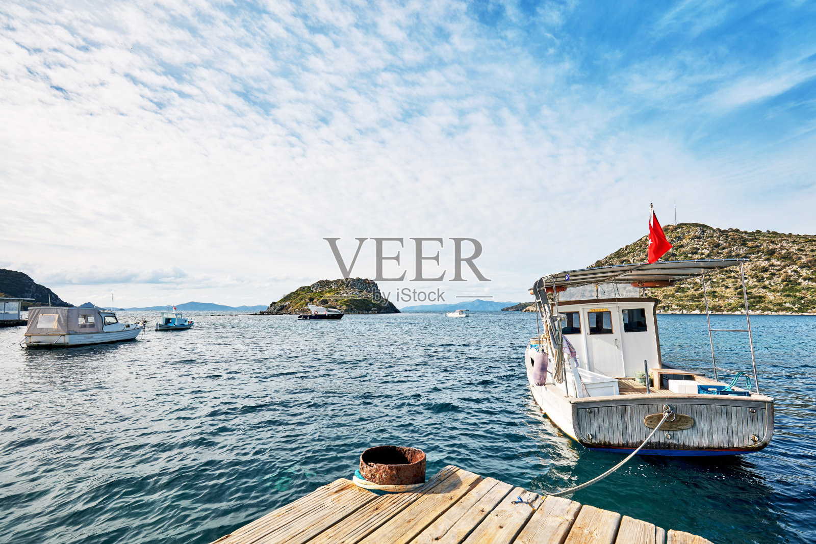 在一个阳光明媚的冬日，渔船停泊在土耳其穆格拉博德拉姆的古穆斯卢克湾的港口。照片摄影图片