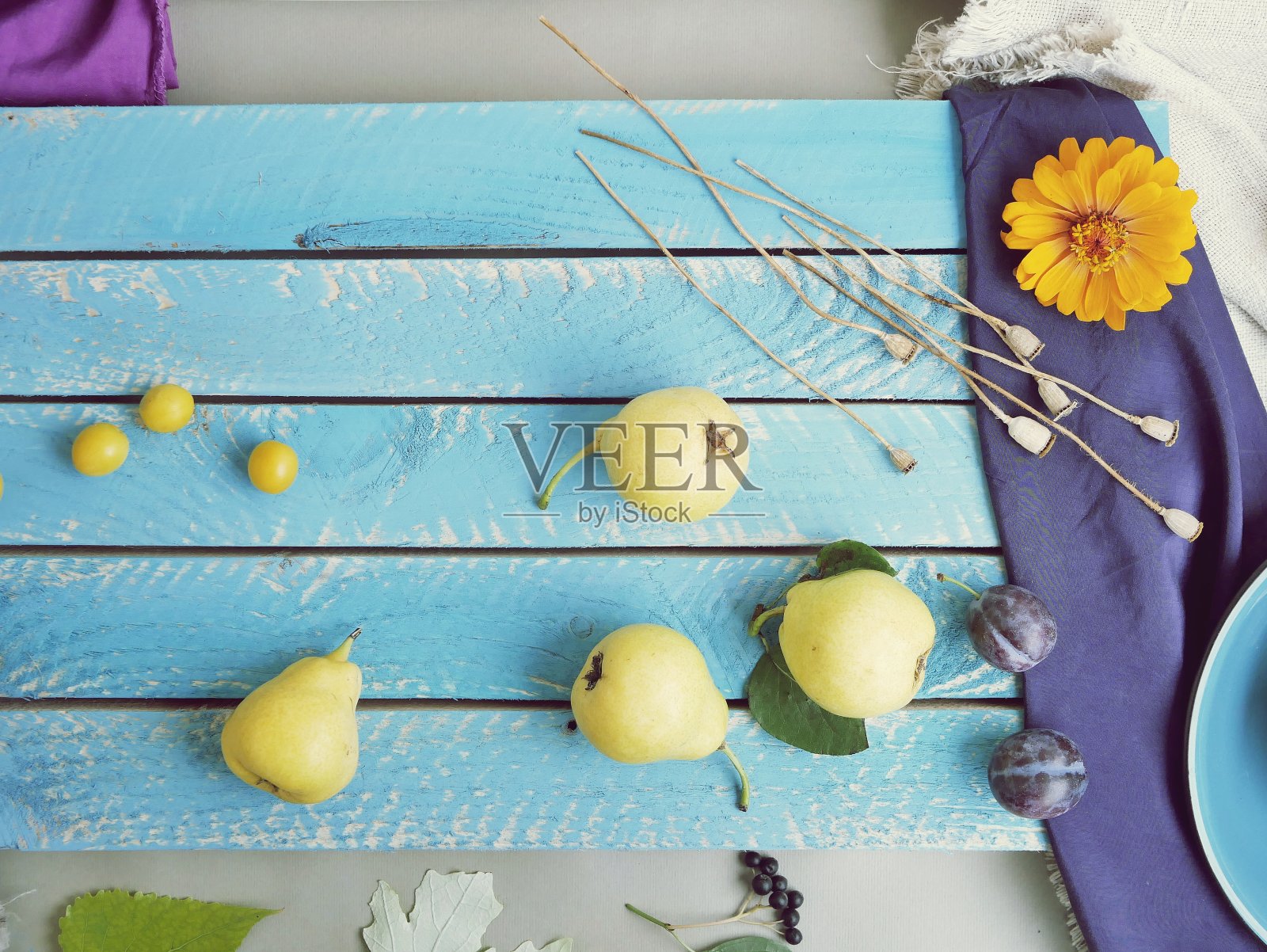 黄熟的梨子和李子散落在一张蓝色的木桌上照片摄影图片