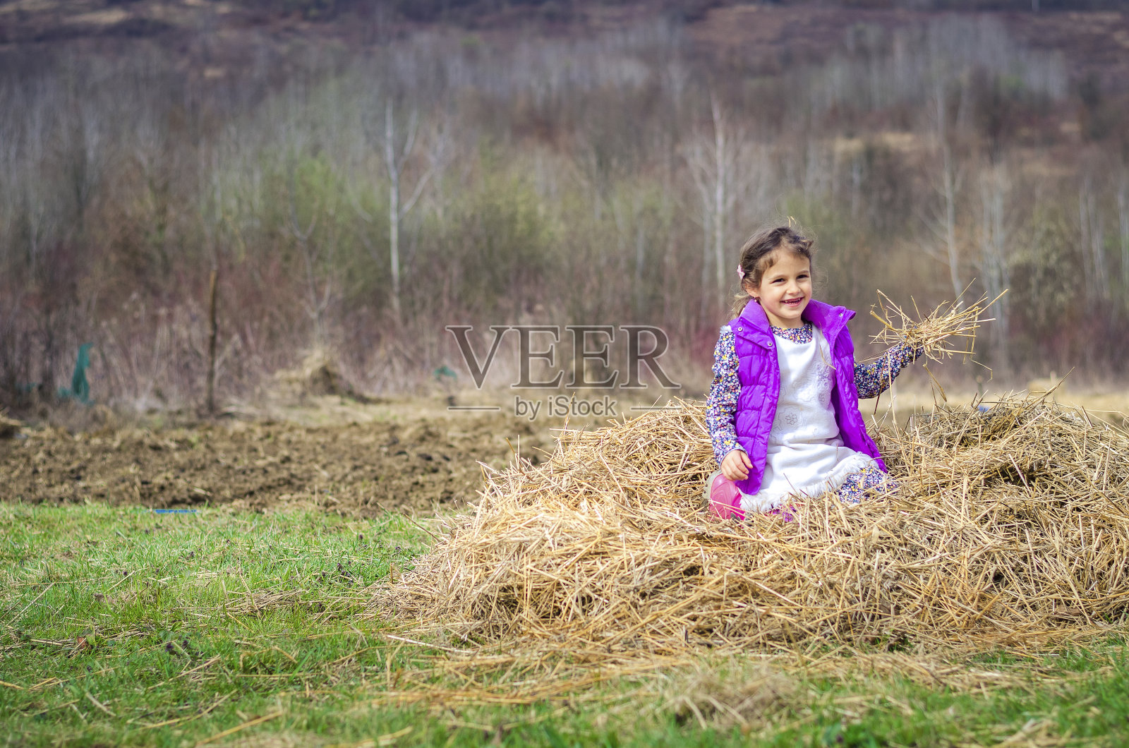 小女孩坐在农场的一堆干草上照片摄影图片