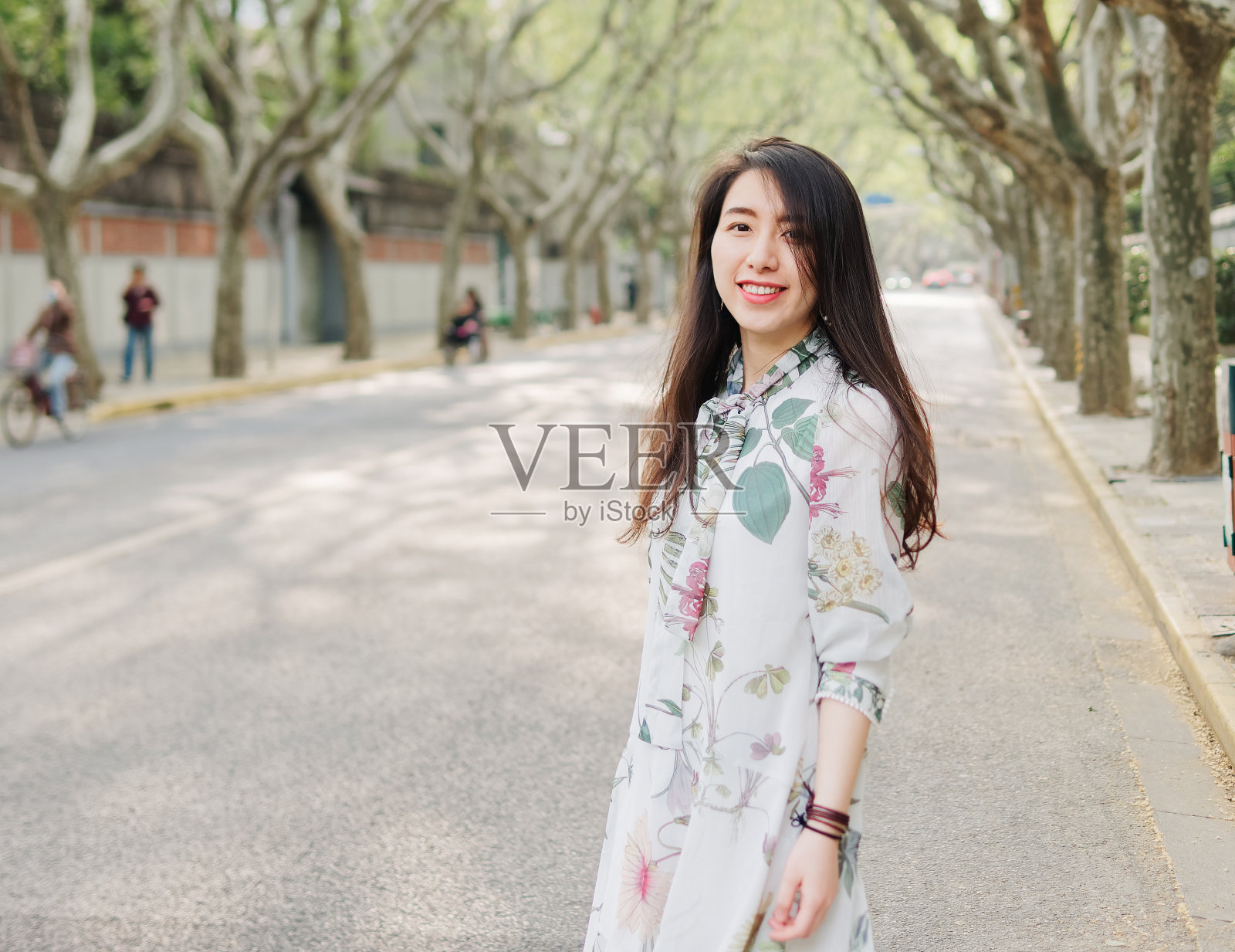 户外肖像的年轻美丽时尚的中国女士在休闲多彩的服装站和微笑在阳光明媚的上海街道的相机。女性时尚。城市生活方式的概念。照片摄影图片