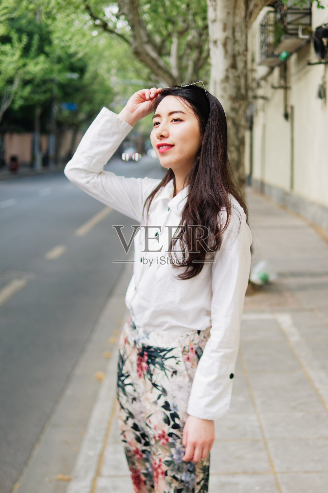 户外肖像年轻美丽时尚的中国女士在休闲衣服站和微笑看在阳光明媚的上海街道。女性时尚。城市生活方式的概念。照片摄影图片
