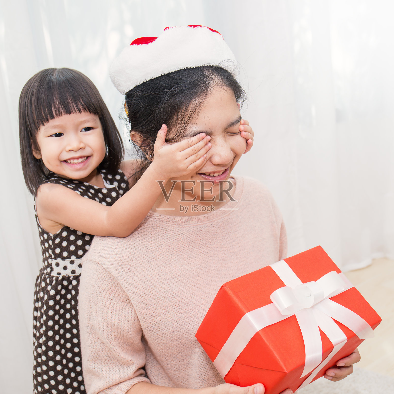 亚洲小女孩用礼盒给妈妈一个惊喜。节礼日、生日、圣诞节和motherâ的日子概念。照片摄影图片