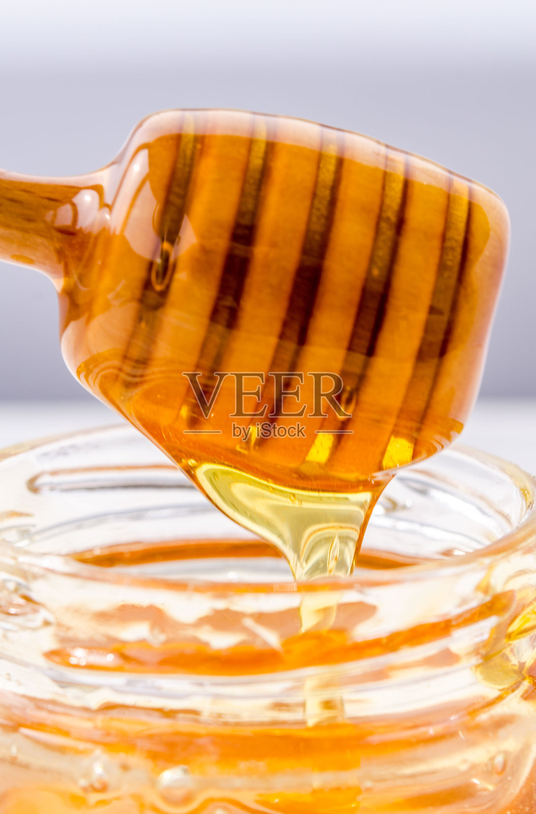 蜂蜜从木制的蜂蜜匙里流出来，非常漂亮照片摄影图片