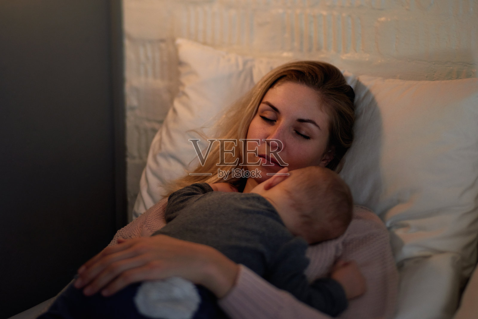 疲惫的母亲小睡，而婴儿睡在她的身上照片摄影图片