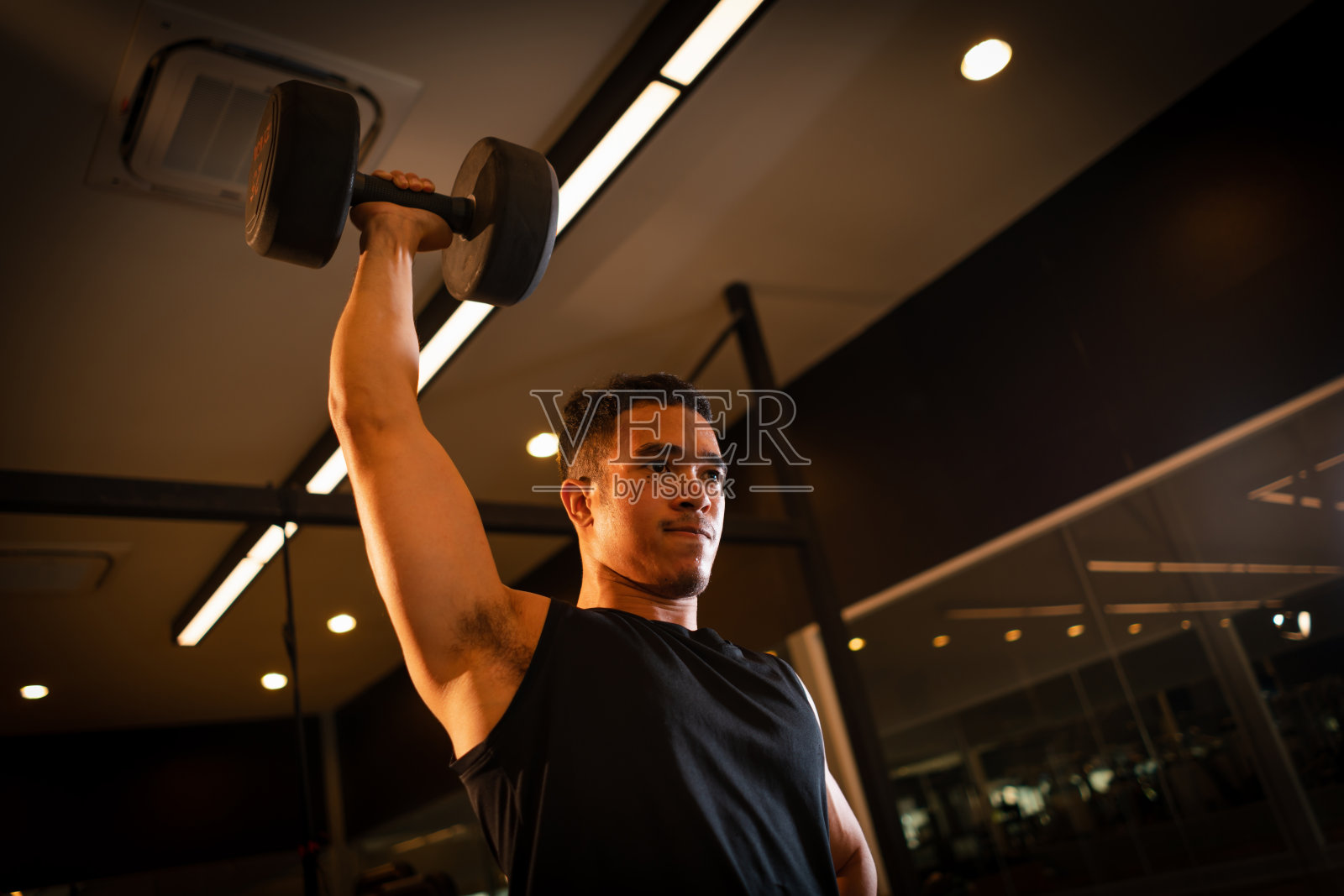 运动员用哑铃练习进行手臂耐力训练，以加强和调理肩膀肌肉。重量训练的概念。照片摄影图片