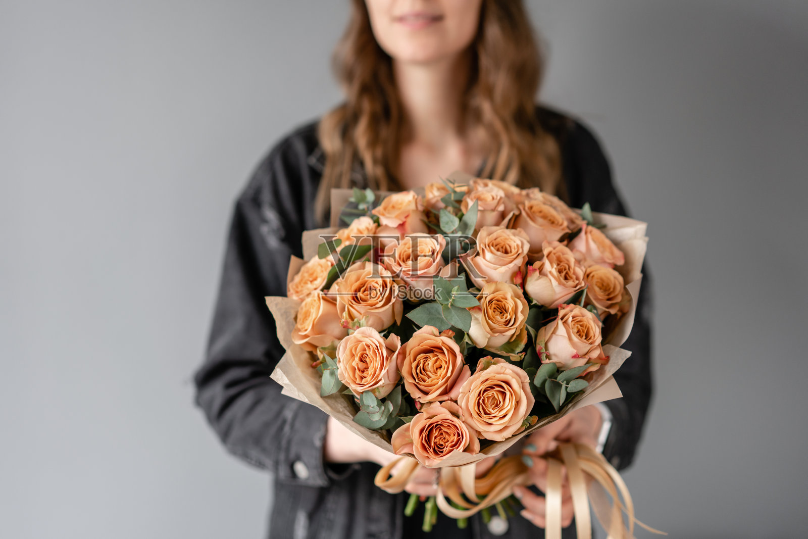 花朵咖啡色，卡布奇诺玫瑰加桉树。女人手里拿着漂亮的小花束。花卉商店的概念。鲜花交付照片摄影图片