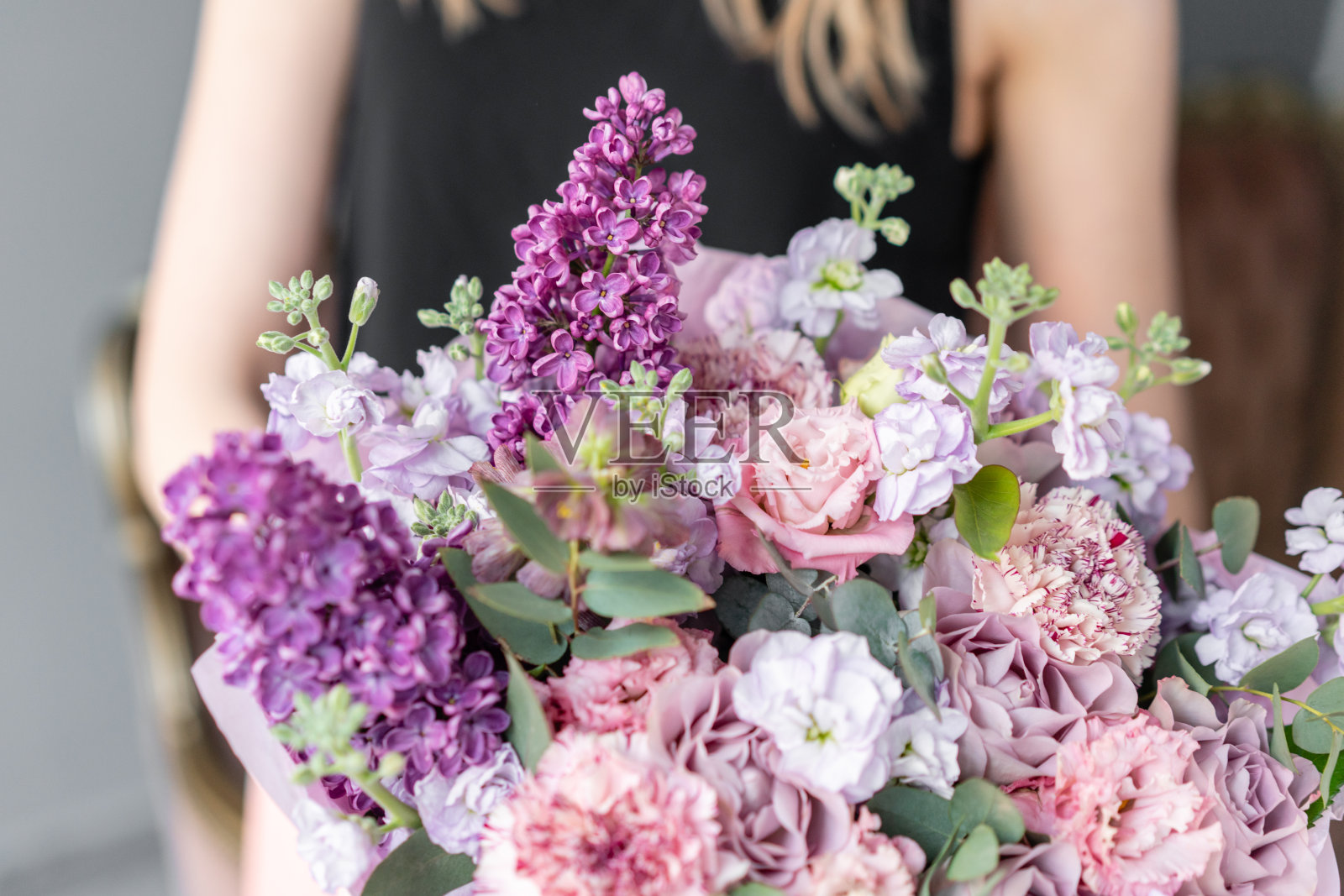 花店。女人手里拿着一束美丽的混合鲜花。花店花匠的工作。精致柔和的颜色。新鲜切花。粉红色和淡紫色照片摄影图片