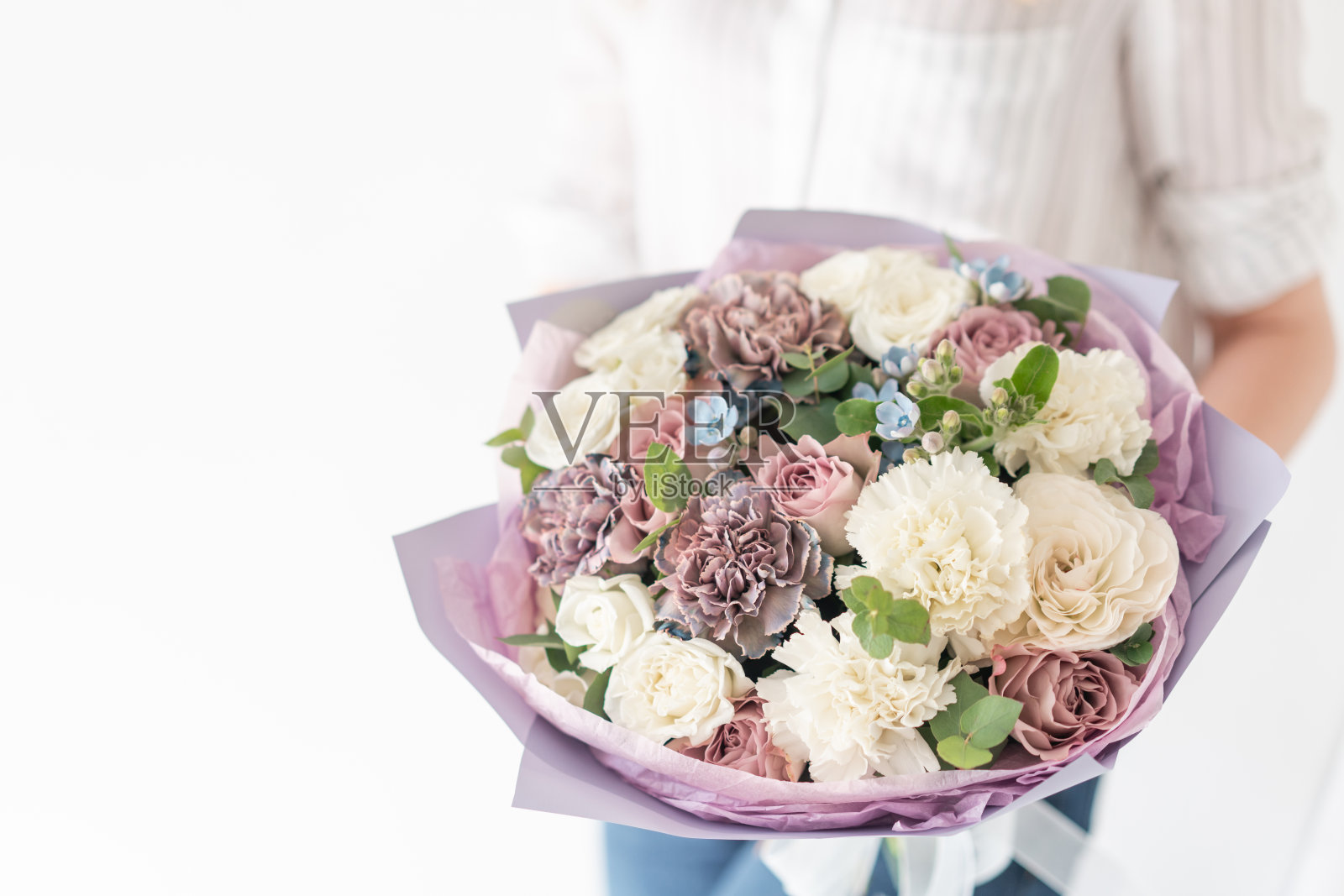 女人手里拿着一束美丽的混合鲜花。花店花匠的工作。精致柔和的颜色。新鲜切花。白色和淡紫色照片摄影图片