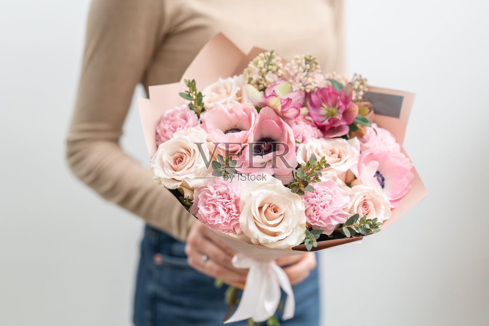 女人手里拿着一束美丽的混合鲜花。花店花匠的工作。精致柔和的颜色。新鲜切花。粉红色和白色照片摄影图片