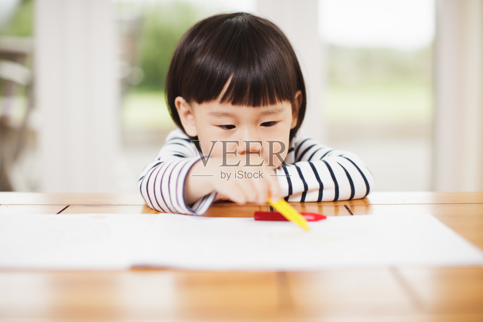 蹒跚学步的小女孩在家里的桌子上画画照片摄影图片