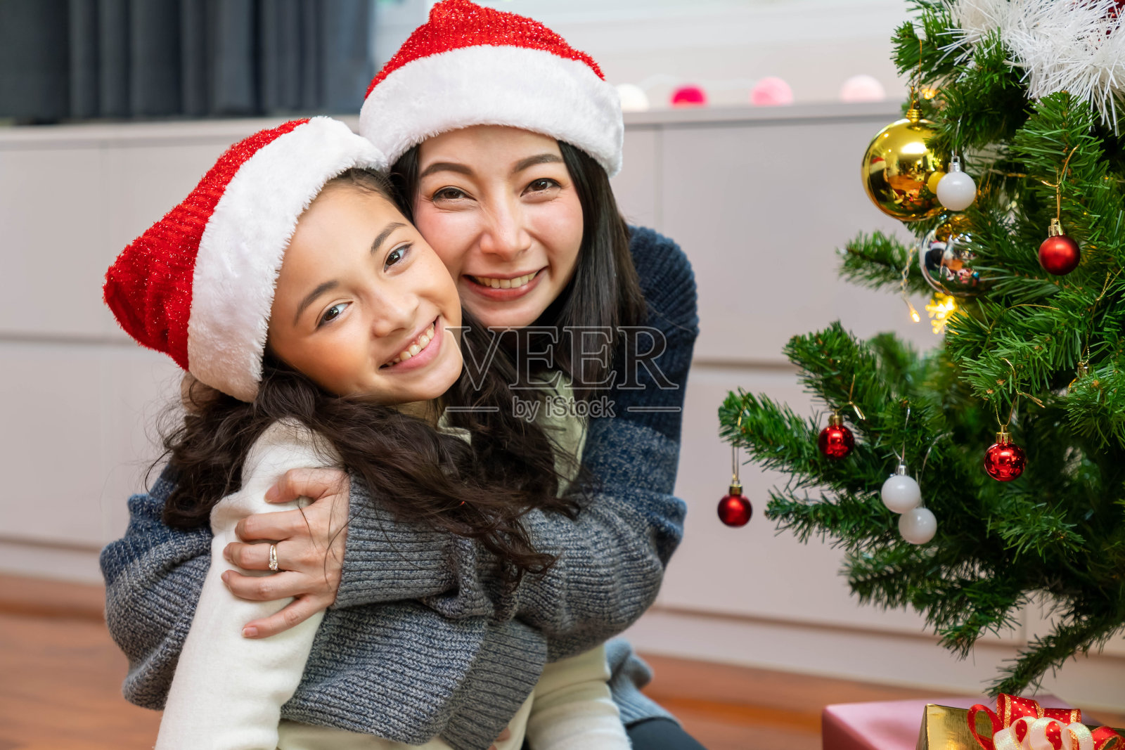 妈妈和女儿在客厅里一起为节日装饰圣诞树;看相机照片摄影图片