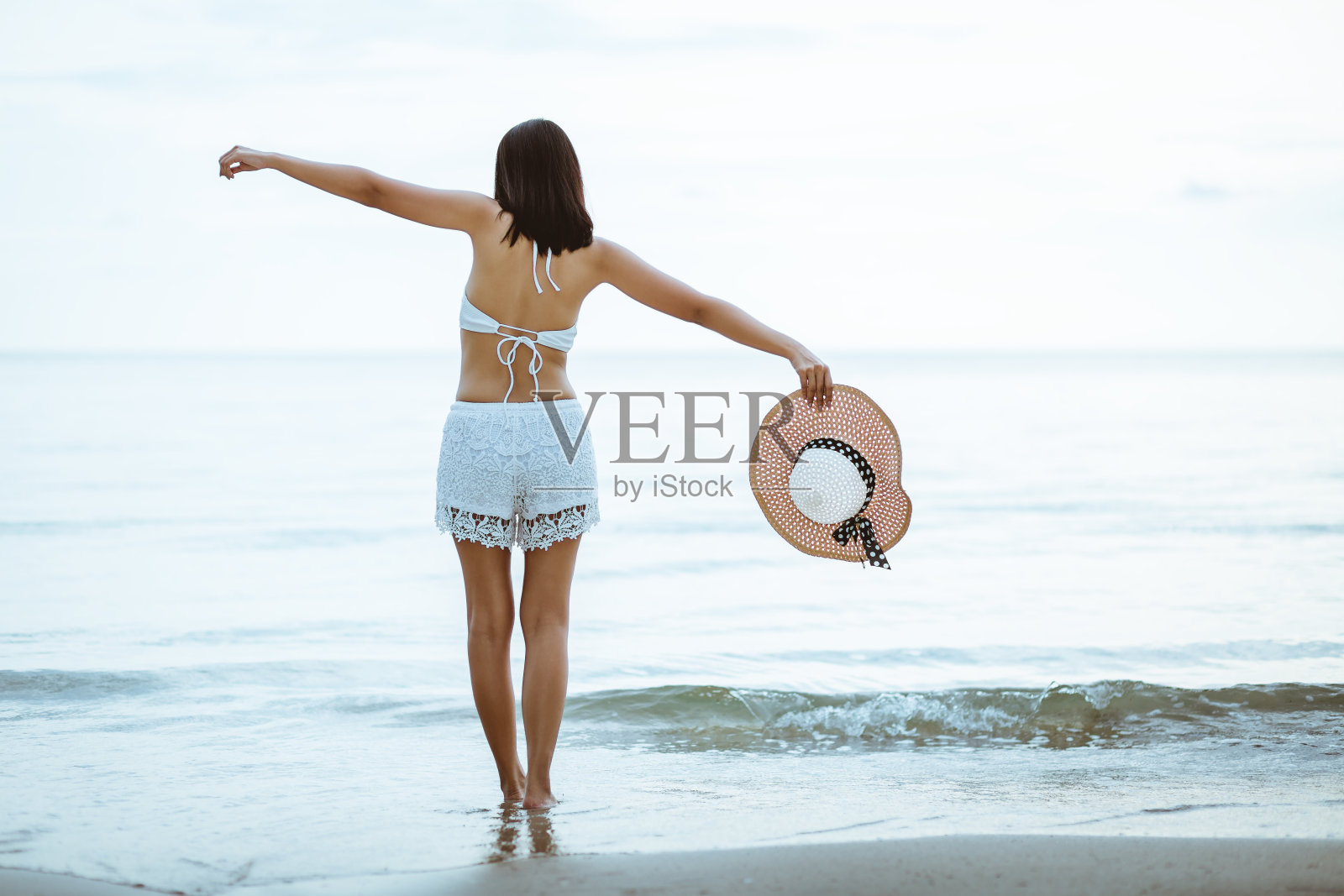 在日落的海滩上散步的女旅行者照片摄影图片