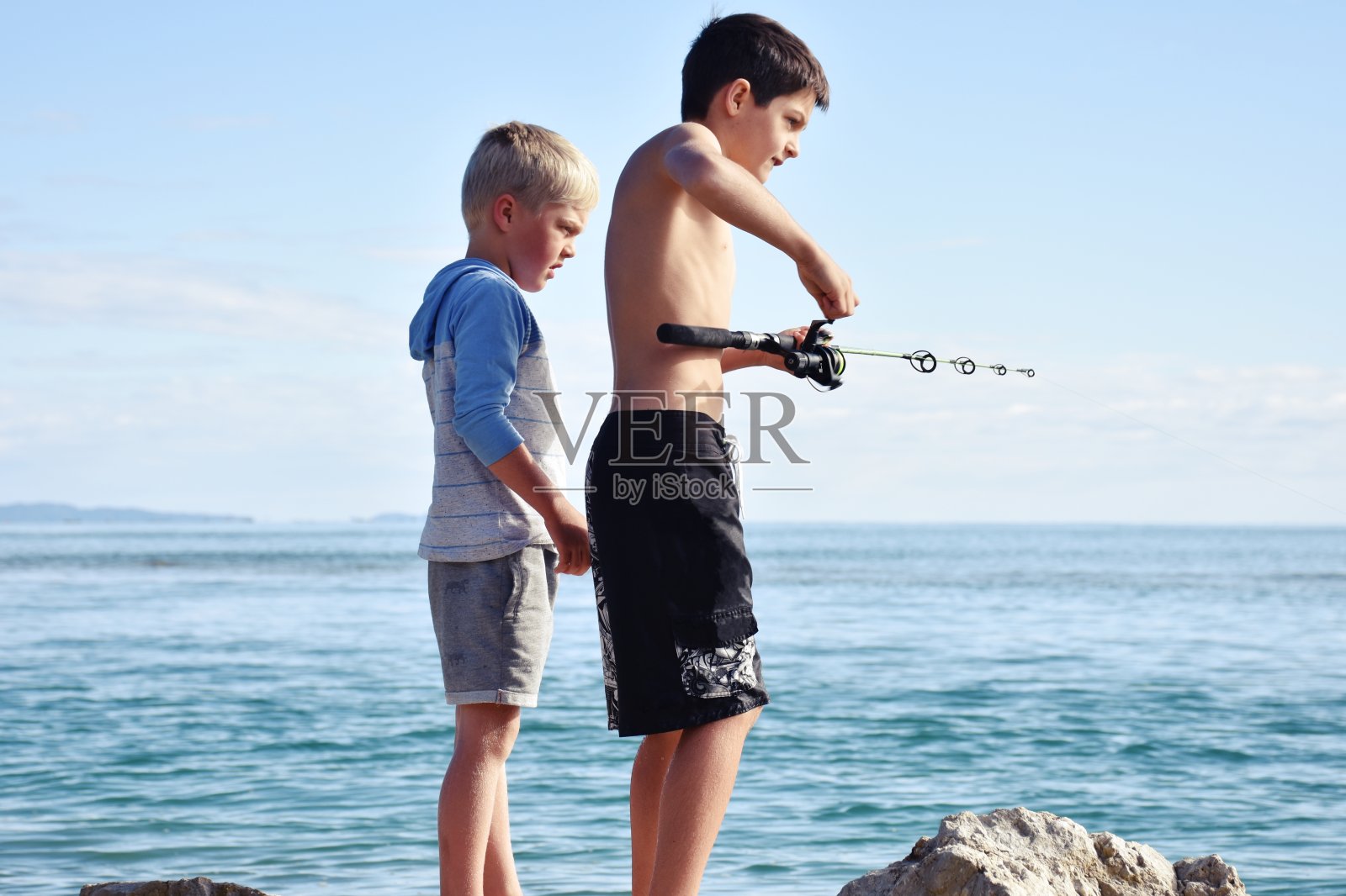 年轻的男孩在海边钓鱼照片摄影图片