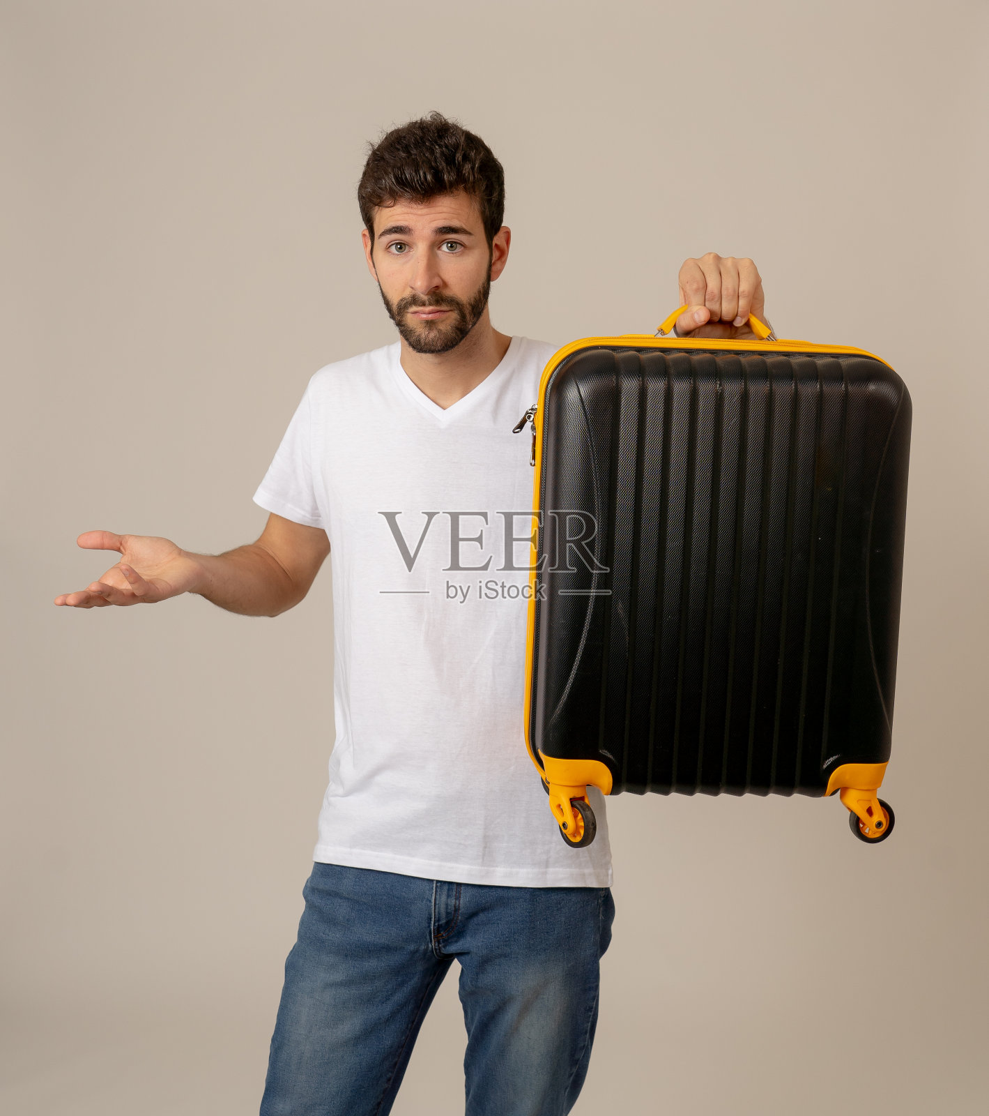 有吸引力的年轻旅行者男子显示行李箱孤立在中性背景。广告风格形象为旅人存储空间、旅游和旅游度假的概念。照片摄影图片