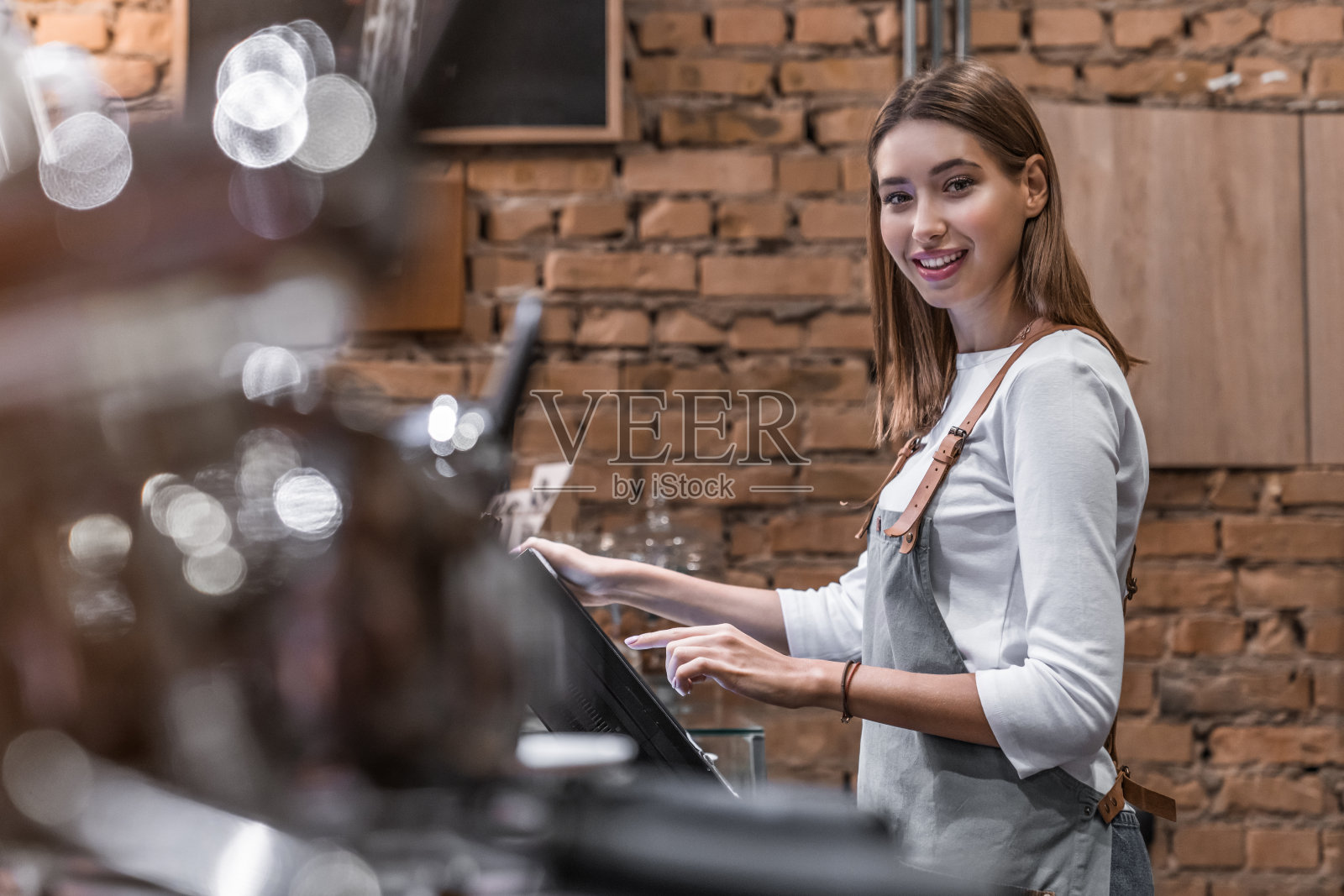 肖像快乐的年轻女子在柜台与现金箱工作在咖啡店照片摄影图片